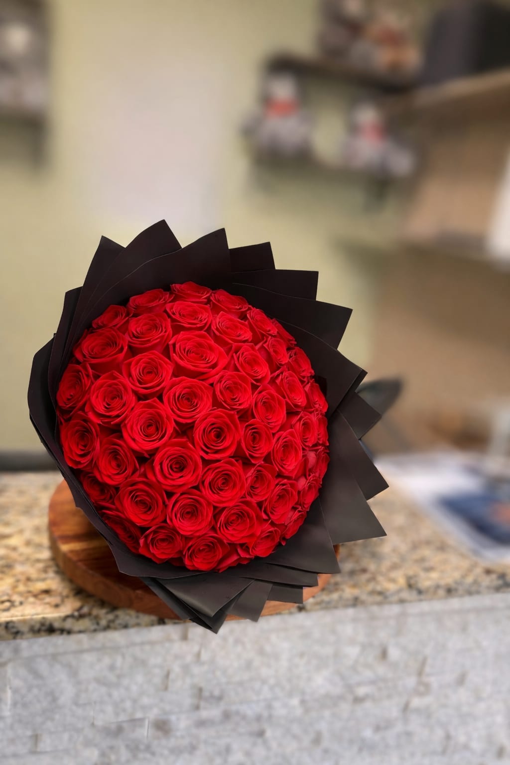 Round bouquet of red roses wrapped in black paper