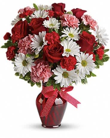 Red roses and white daisies in a red vase with a polka-dot ribbon