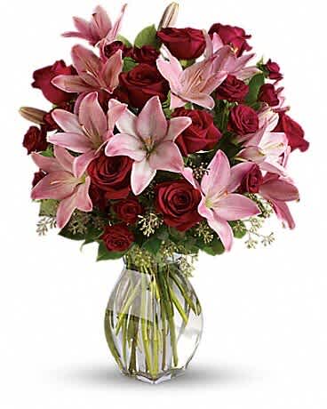 Bouquet of red roses and pink lilies in a clear glass vase