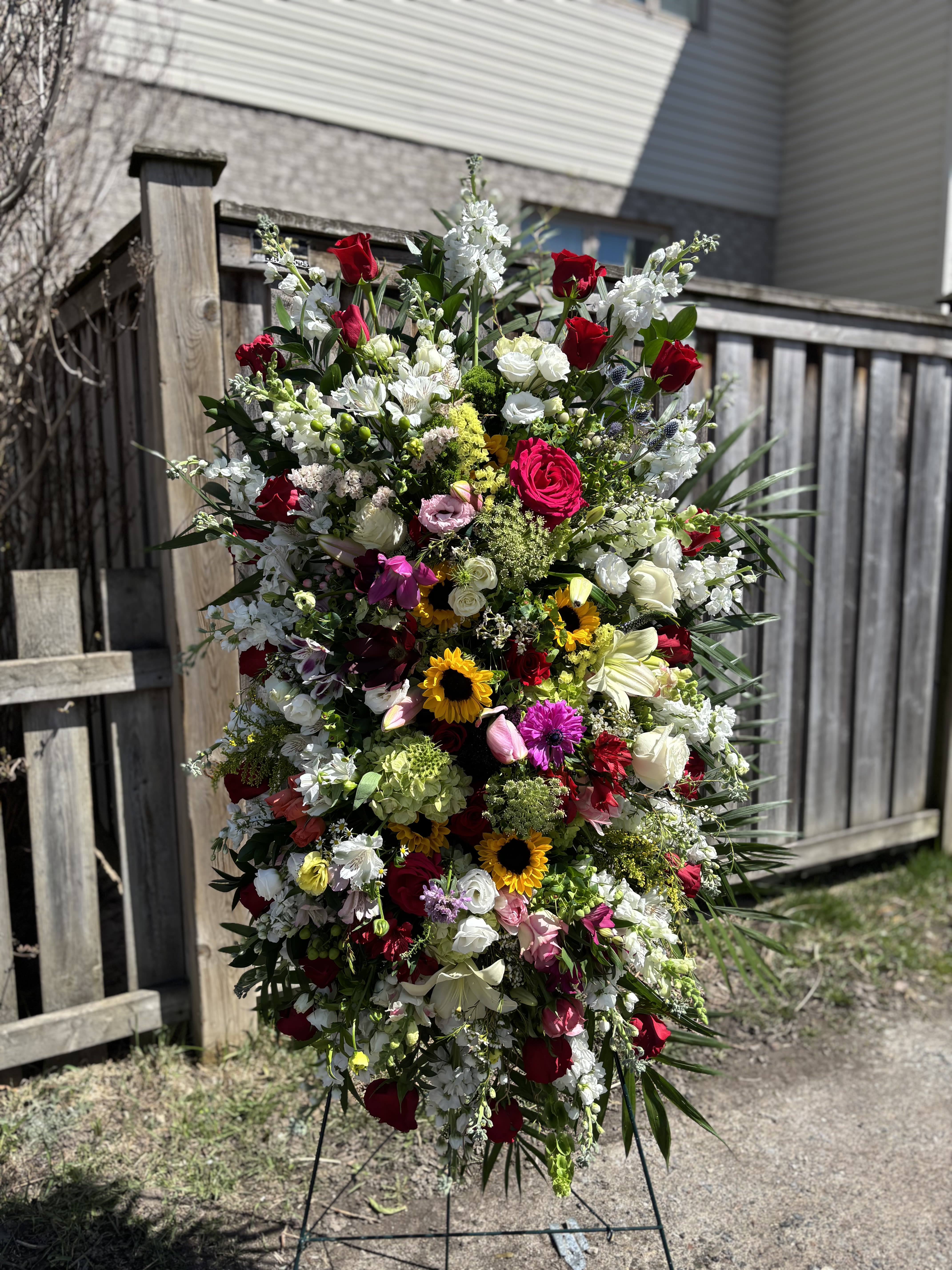 Large standing floral spray with red, white, pink, and yellow flowers