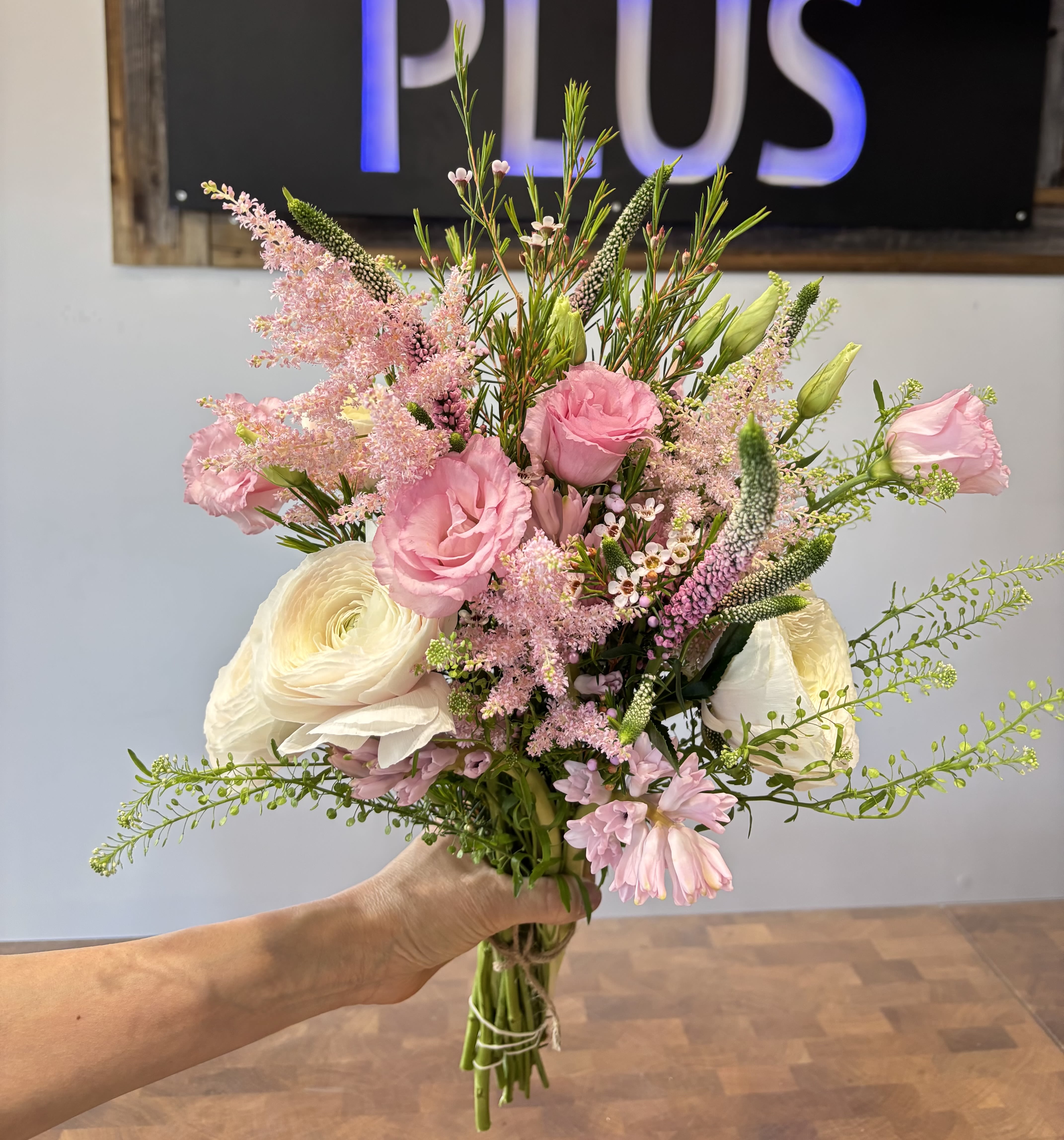 Handheld bouquet of pink and white flowers with airy greenery