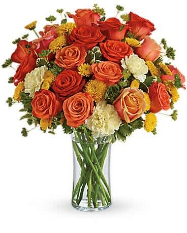 Bouquet of orange and red roses with yellow accents in a clear glass vase