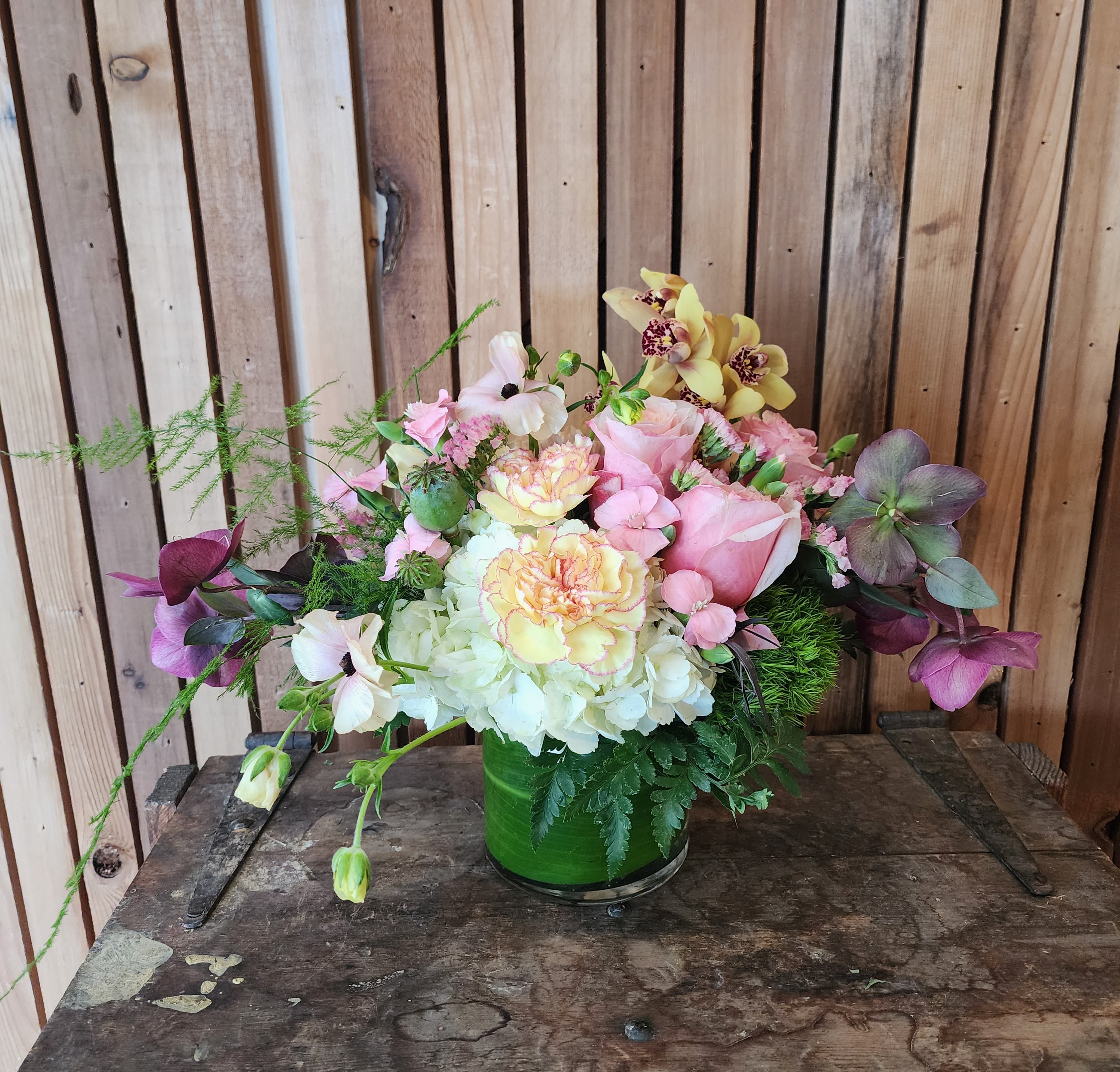 Blush &amp; Buttercream - A low, garden-style arrangement in soft seasonal tones of white, pink, and light yellow, arranged in a leaf-lined vase.