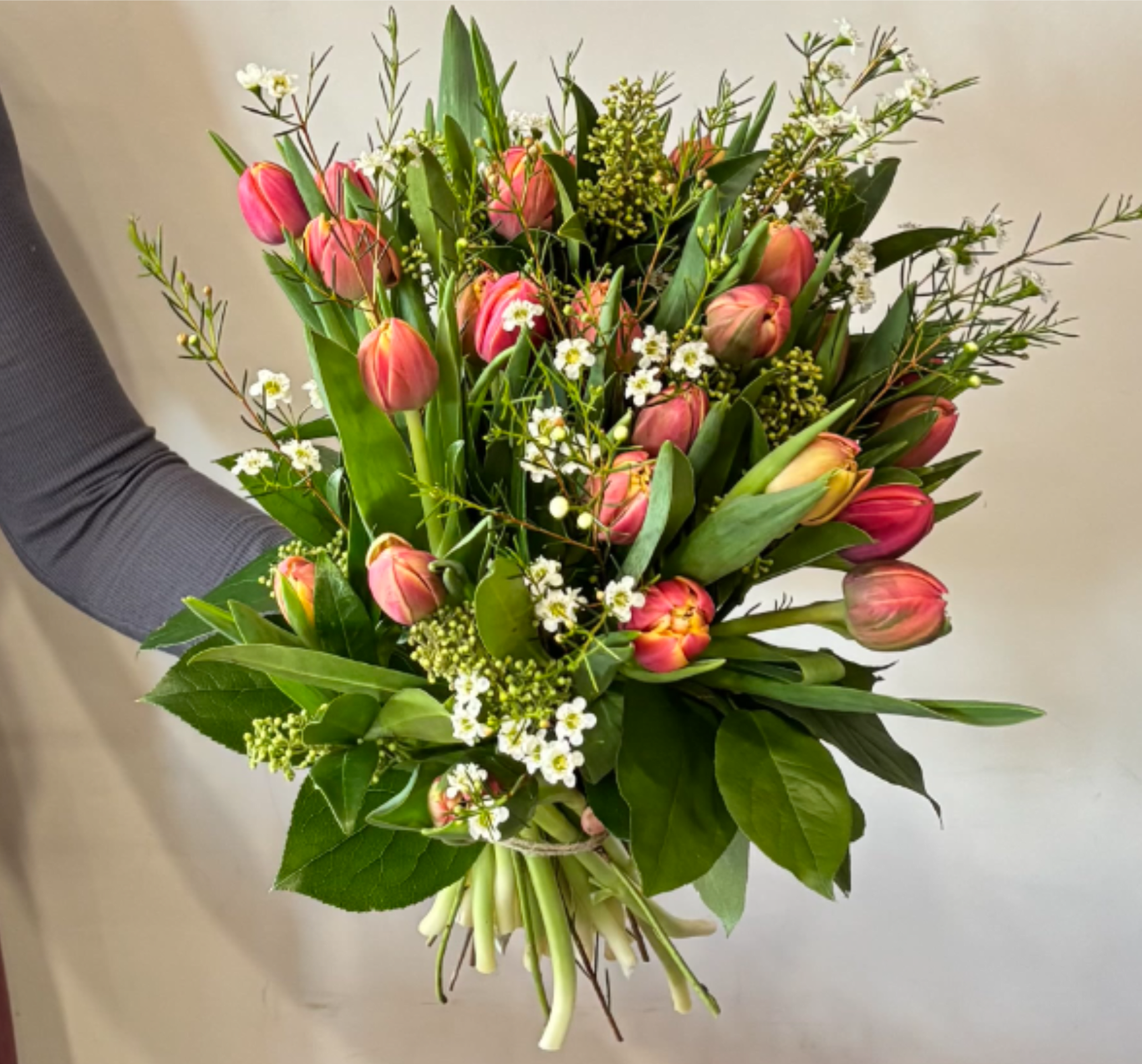 Bouquet of pink tulips with small white filler flowers and greenery