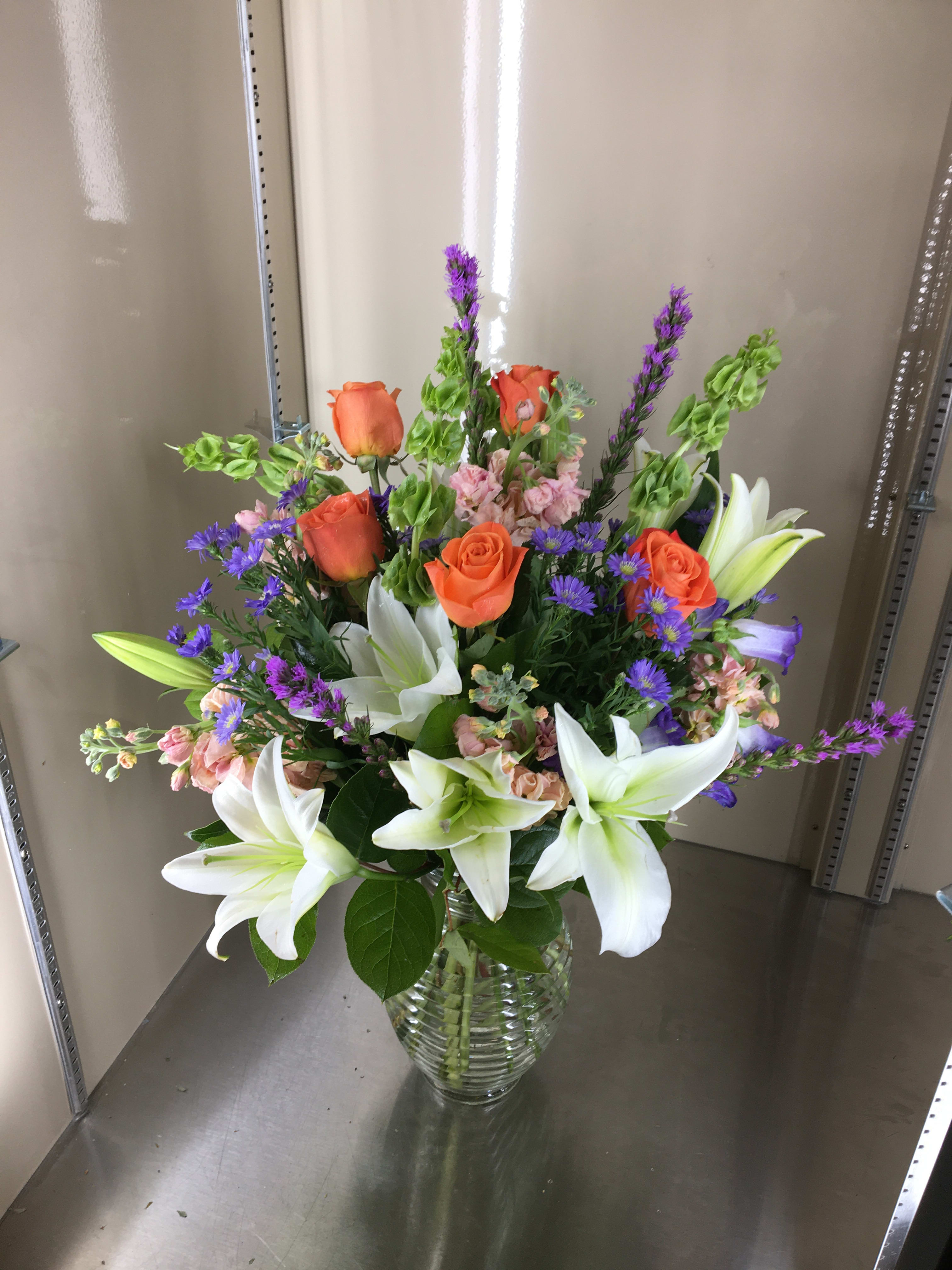 Bouquet of orange roses and white lilies in a glass vase