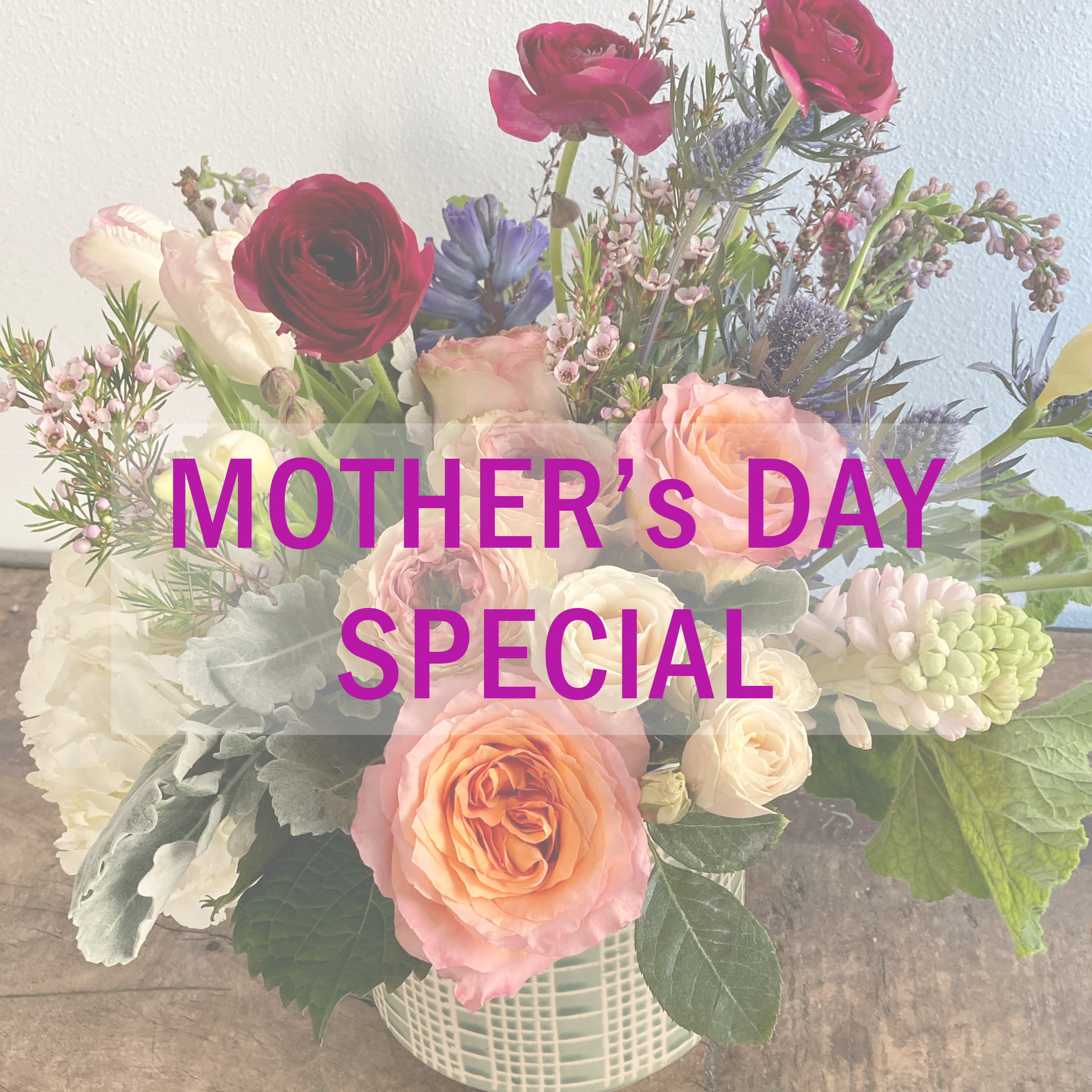 Mixed bouquet of roses, ranunculus, and pastel blooms in a white basket vase