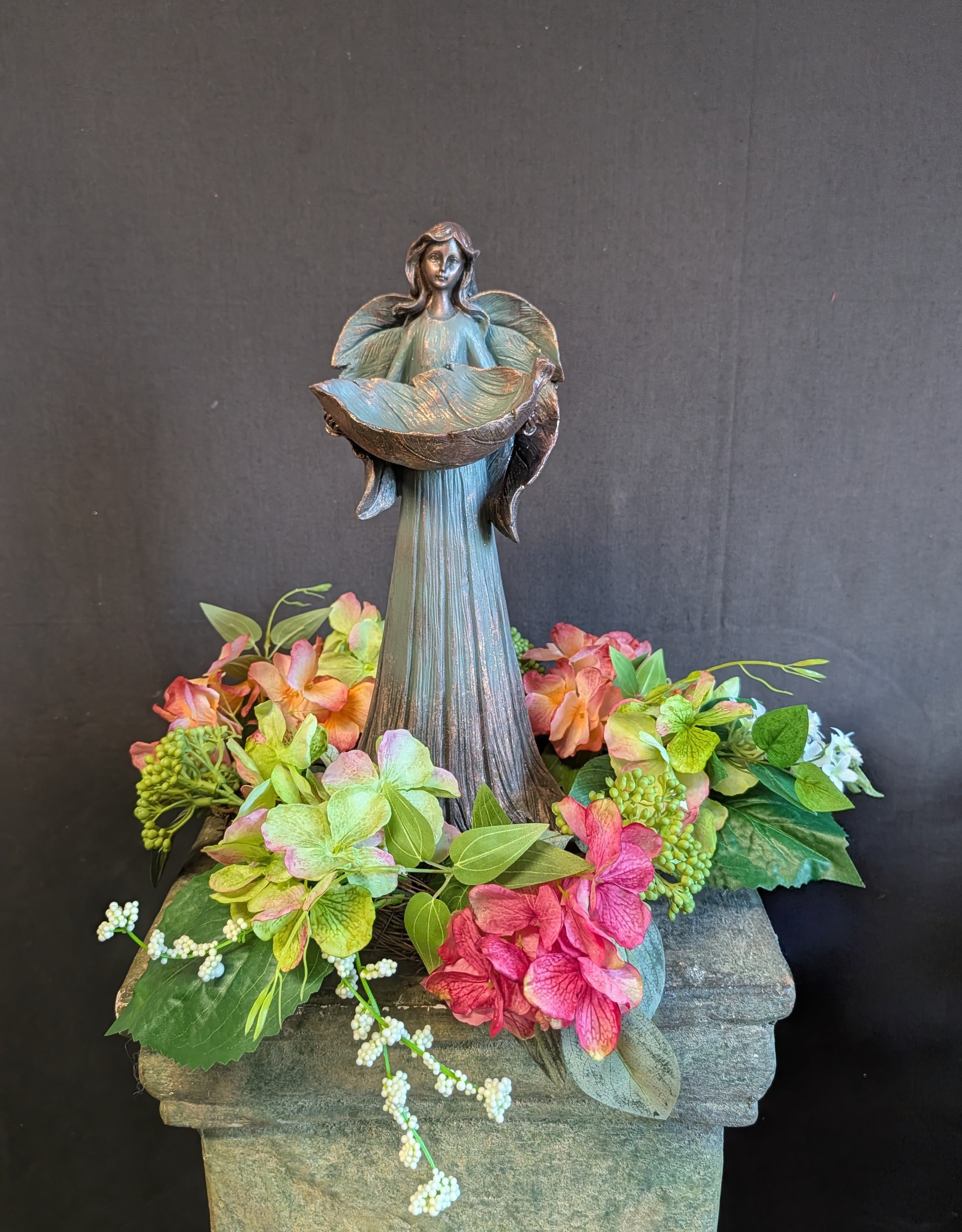 Enchanted Garden Fairy - Bring a touch of peaceful beauty to any space with this Garden Fairy sautute surrounded by colorful faux flowers. This elegant Fairy silhouette is framed by bright, high-quality artificial blooms for a vibrant, long-lasting display.  Perfect as a floral memorial tribute, grave decoration, or sympathy arrangement, this Angel sautute offers the look of fresh flowers without the maintenance. The rich greenery and vivid faux flowers create a striking contrast, symbolizing love, remembrance, and eternal peace.