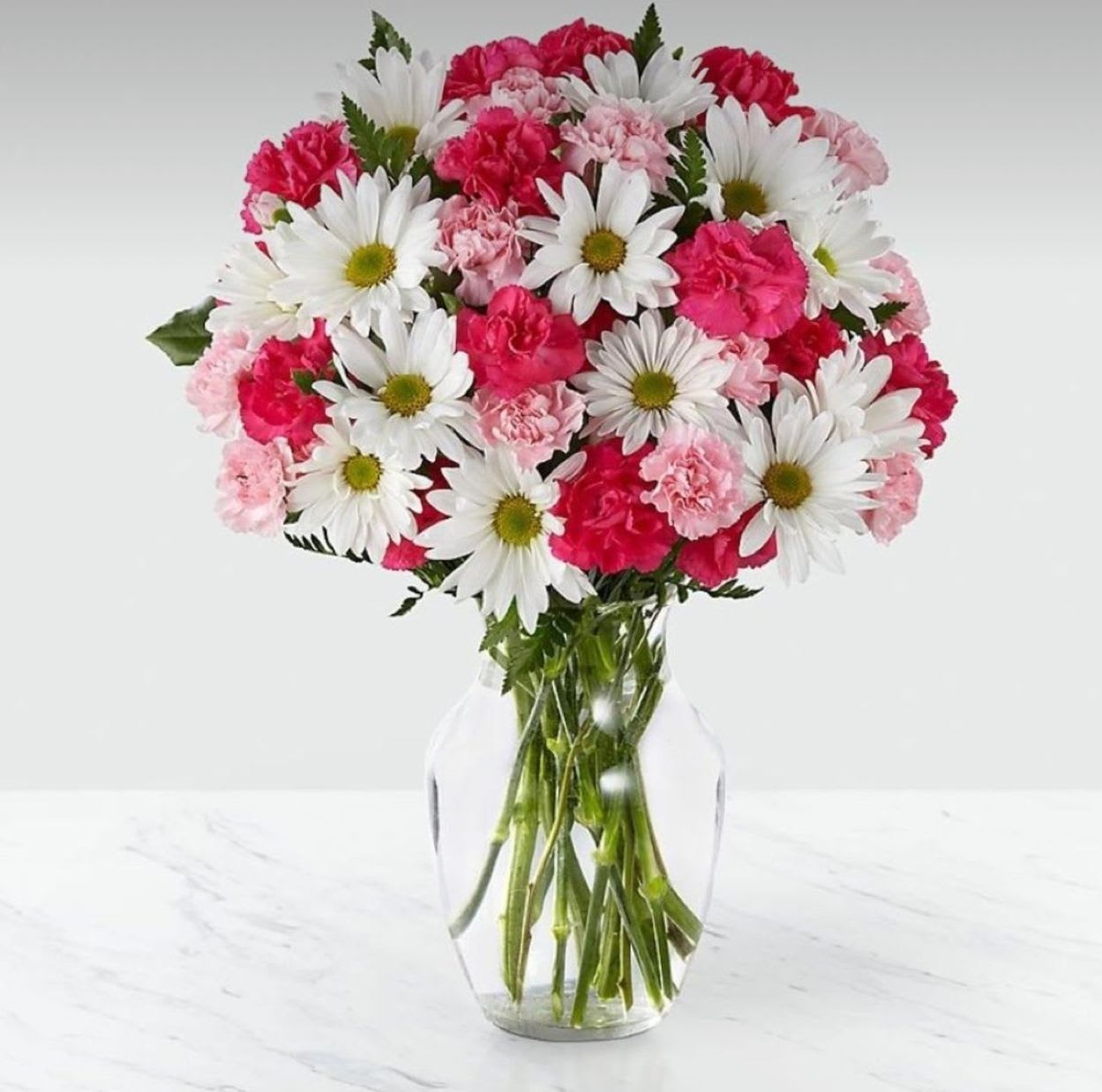 Pink Surprise Bouquet – Soft Pink Birthday Flowers - The Pink Surprise Bouquet is a delightful blend of charm and sweetness — perfect for brightening any birthday celebration. This elegant arrangement features soft pink roses, cheerful daisies, and delicate carnations, complemented by touches of fresh greenery. Designed to express affection, joy, and gratitude, it’s ideal for celebrating someone special. Handcrafted with love by 1-800 Blooms, and available for same-day delivery throughout the Bronx, NY