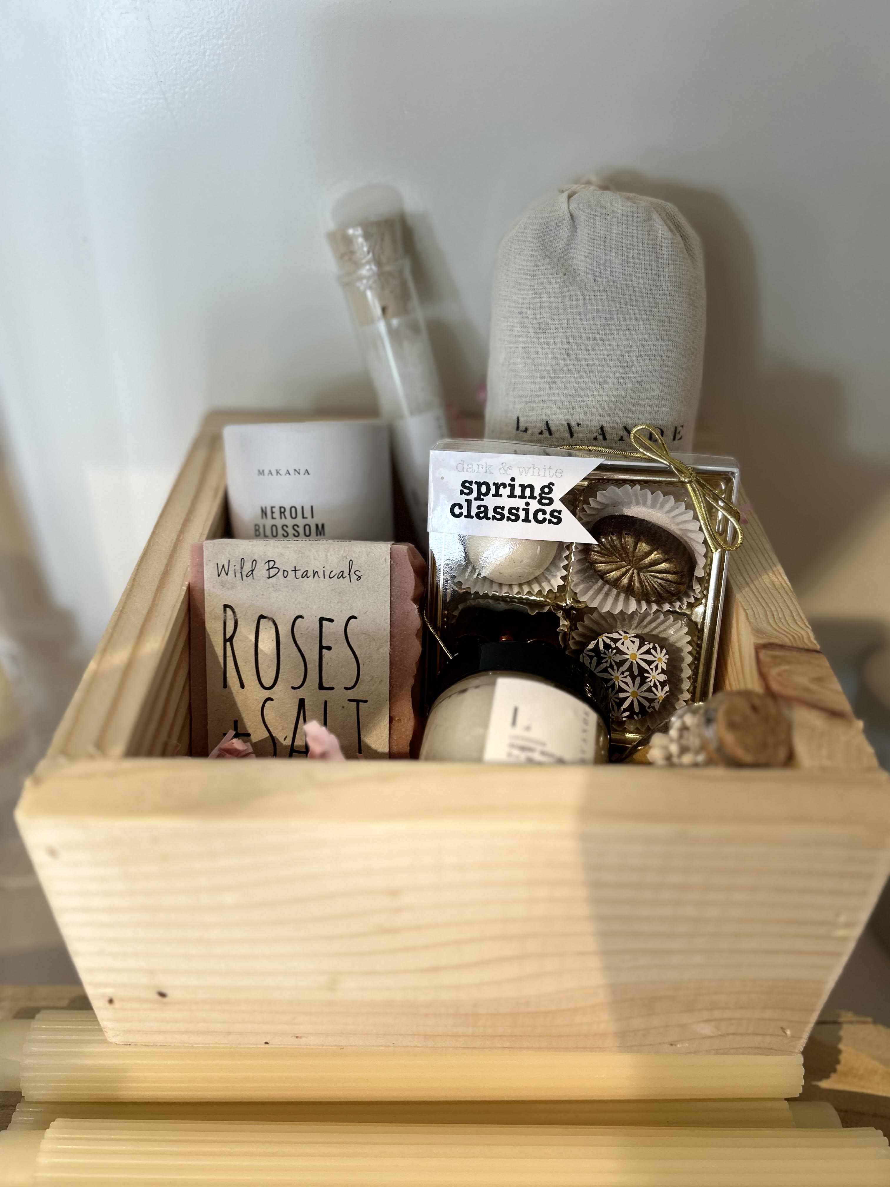 Gift basket with soaps, candles, and chocolates in a wooden crate