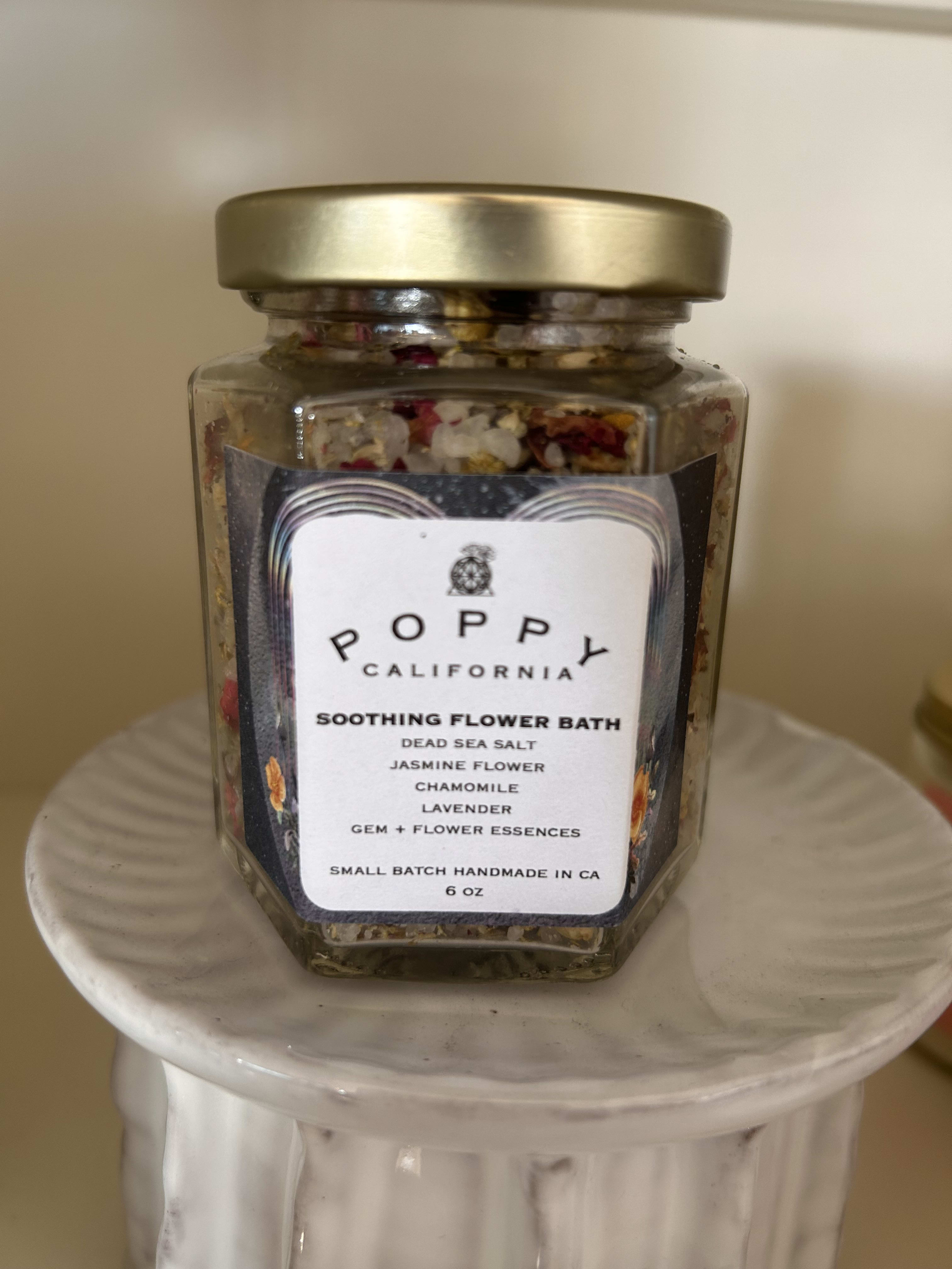 Jar of flower bath salts with a gold lid on a white pedestal
