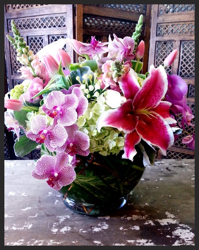 Pink orchids and lilies arranged in a glass vase