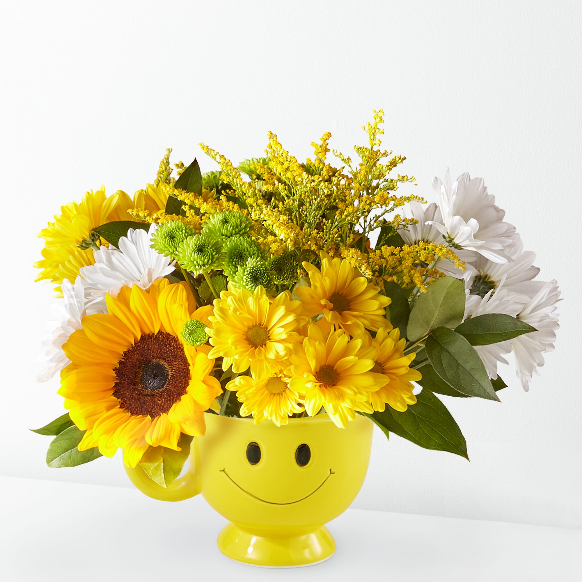 Yellow and white flower arrangement in a smiley-face mug