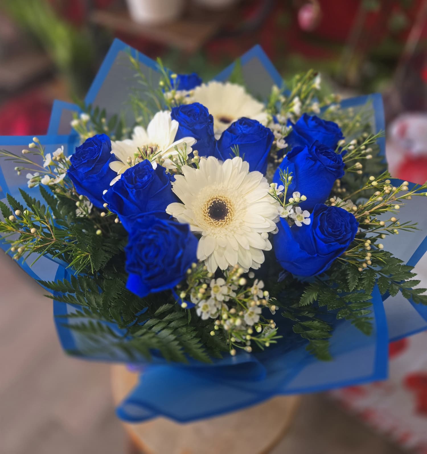 Bouquet of blue roses and white gerbera daisies wrapped in blue paper