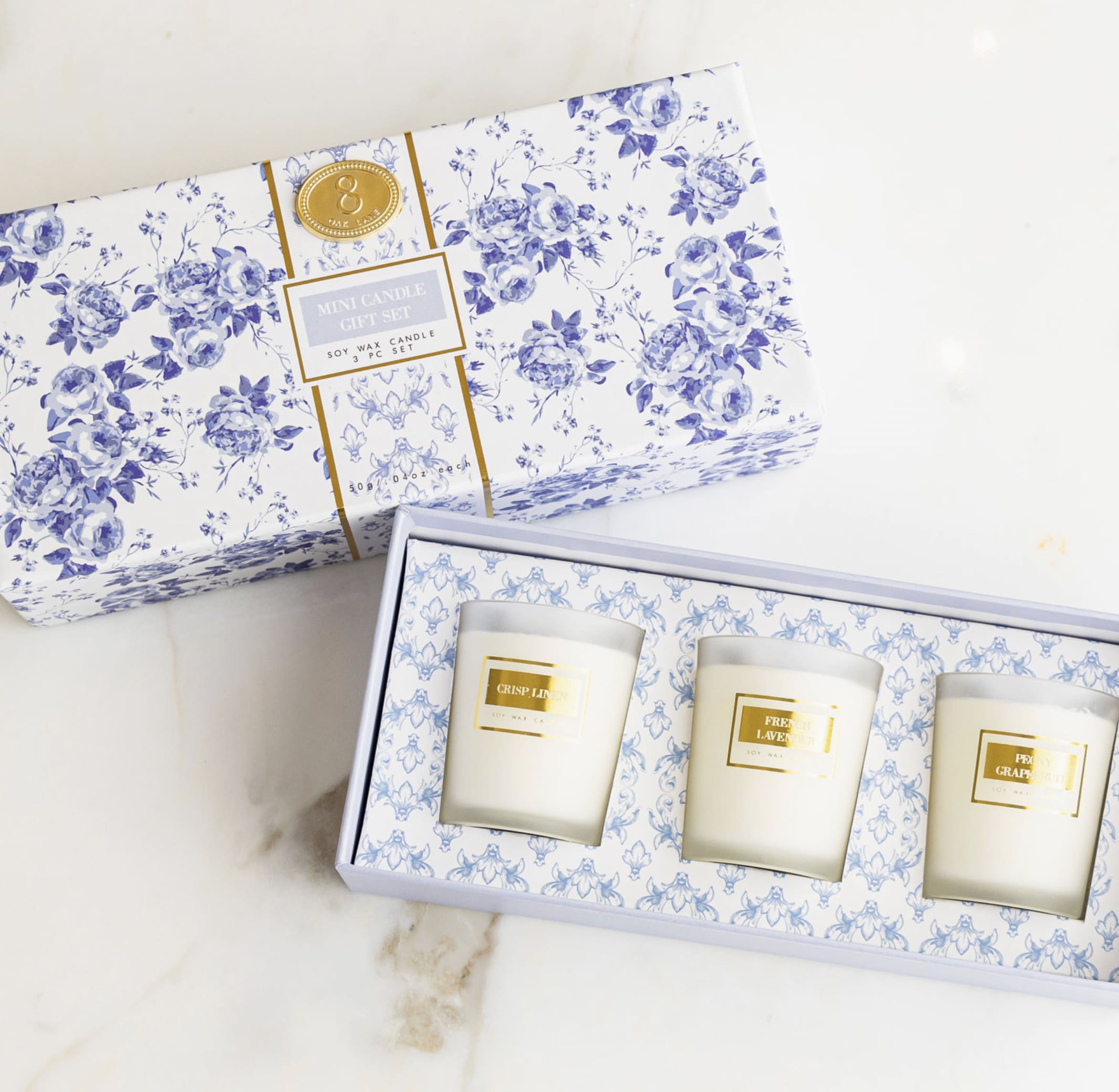 Three scented candles in a floral gift box with blue-and-white packaging