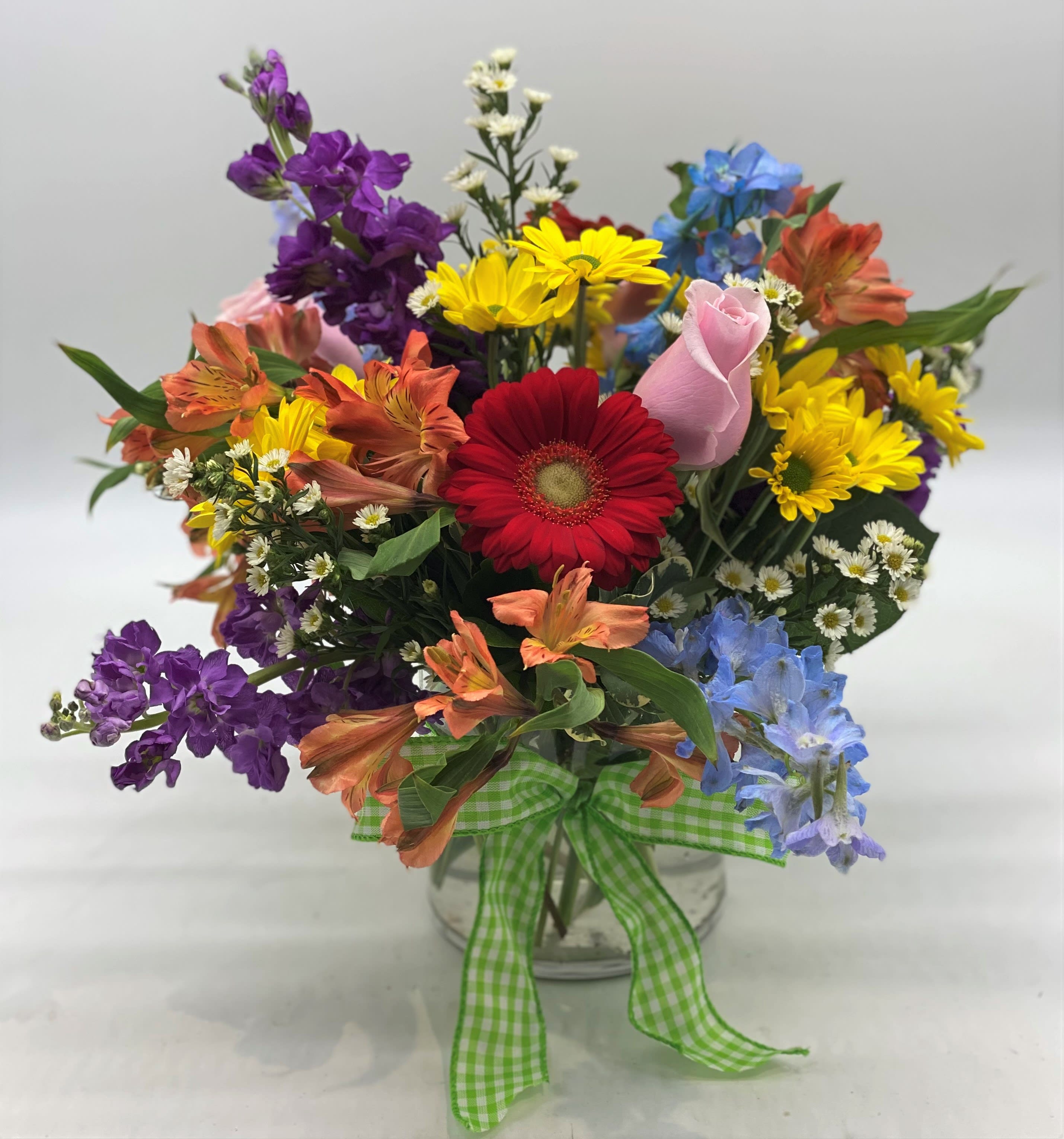 Colorful mixed bouquet in a clear glass vase with a green gingham ribbon