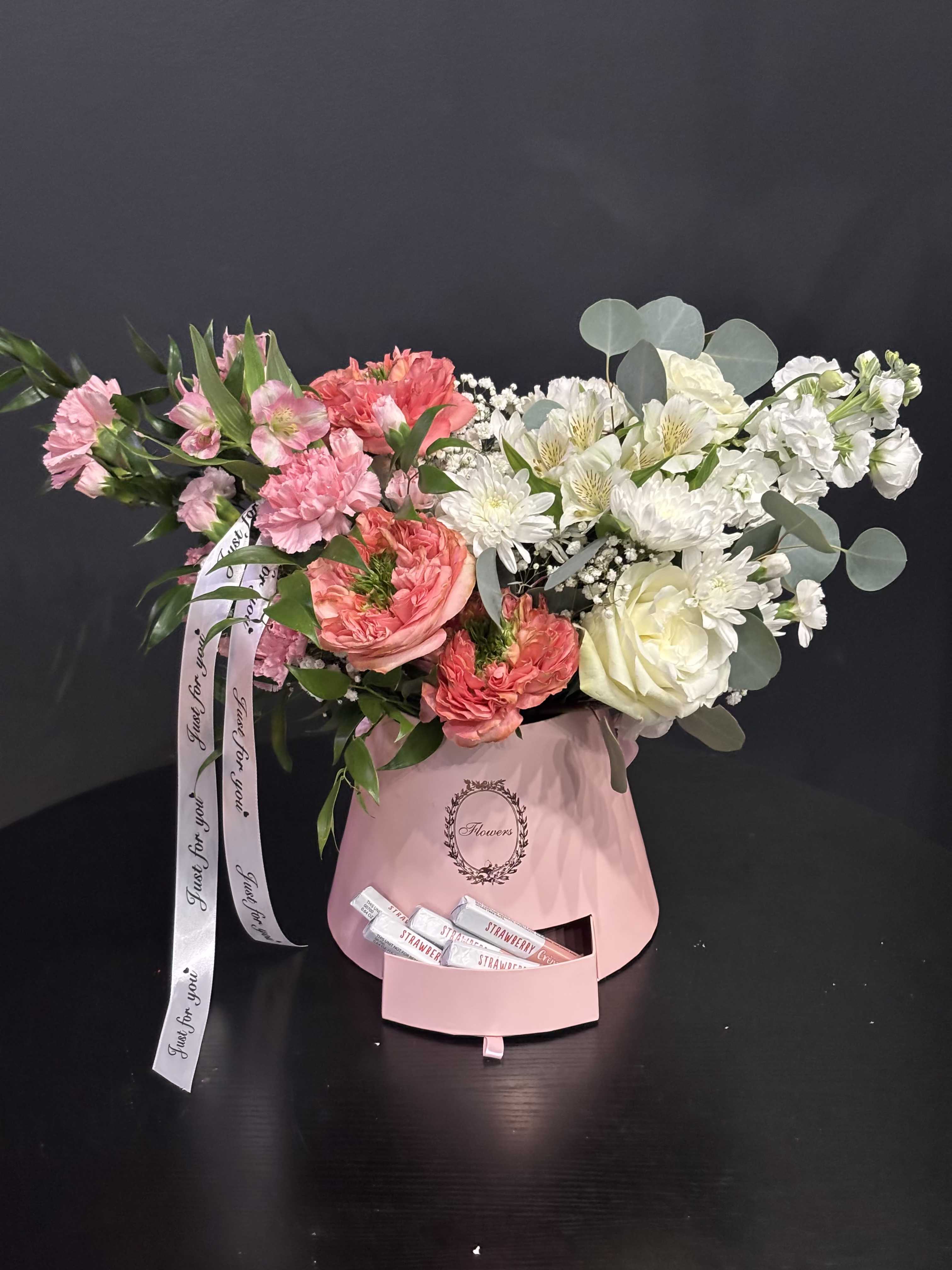 Pink kiss - A delicate flower arrangement in a hat box with a pull-out drawer for chocolates — a gift with a double surprise: fresh blooms and sweet treats in one elegant design. The flowers are arranged in floral foam inside the box to keep them fresh and beautifully shaped, while the lower drawer is designed to hold chocolates or other small gifts. The photo shows a soft white-and-pink version that looks especially romantic and gentle. Upon request, the arrangement can be created in any color palette — from light pastels to bold, vibrant tones — according to the client’s preference. Perfect for Valentine’s Day, birthdays, anniversaries, or as a stylish gesture of appreciation.