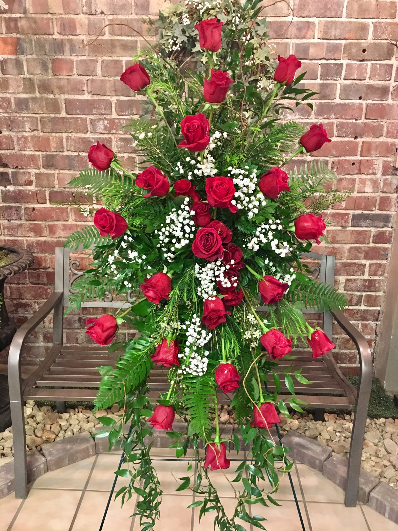 Tall standing arrangement of red roses with white baby's breath