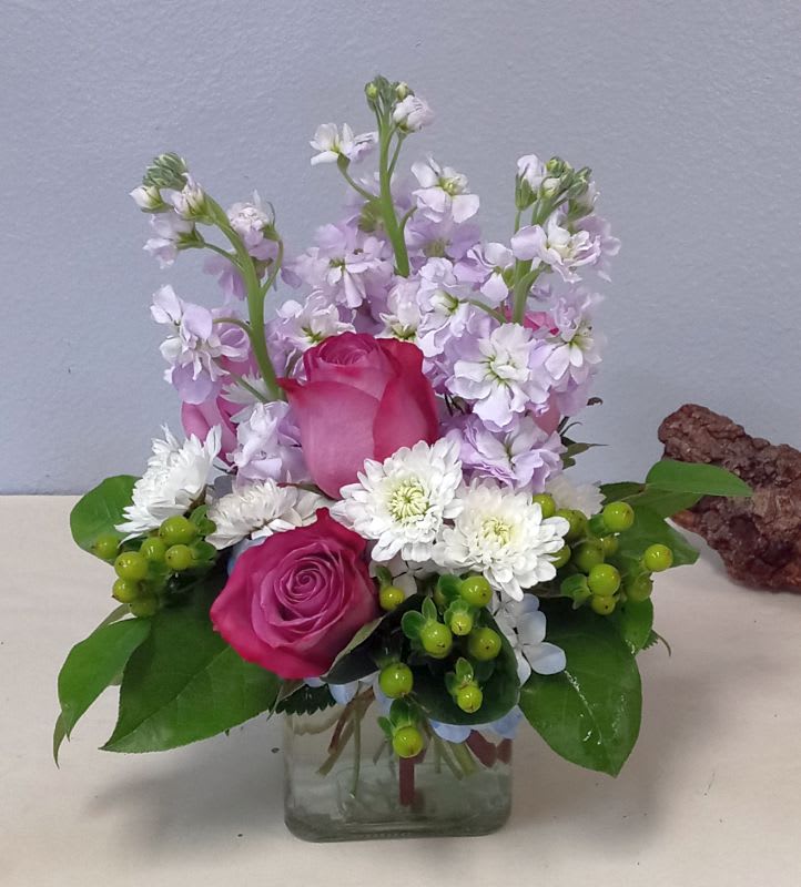 Pink roses and white flowers arranged in a clear glass vase