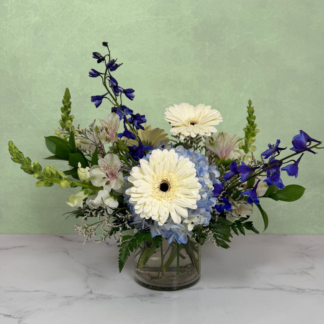 Blue and white flower arrangement in a clear glass vase
