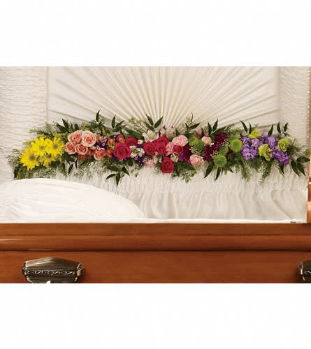 Colorful floral spray arranged on a casket with roses and daisies