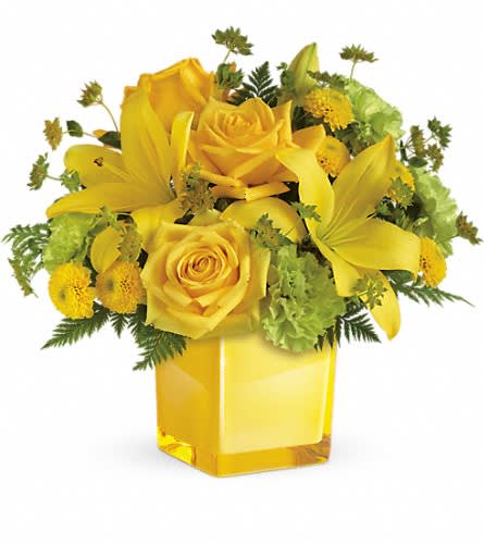Yellow roses and lilies arranged in a square glass vase