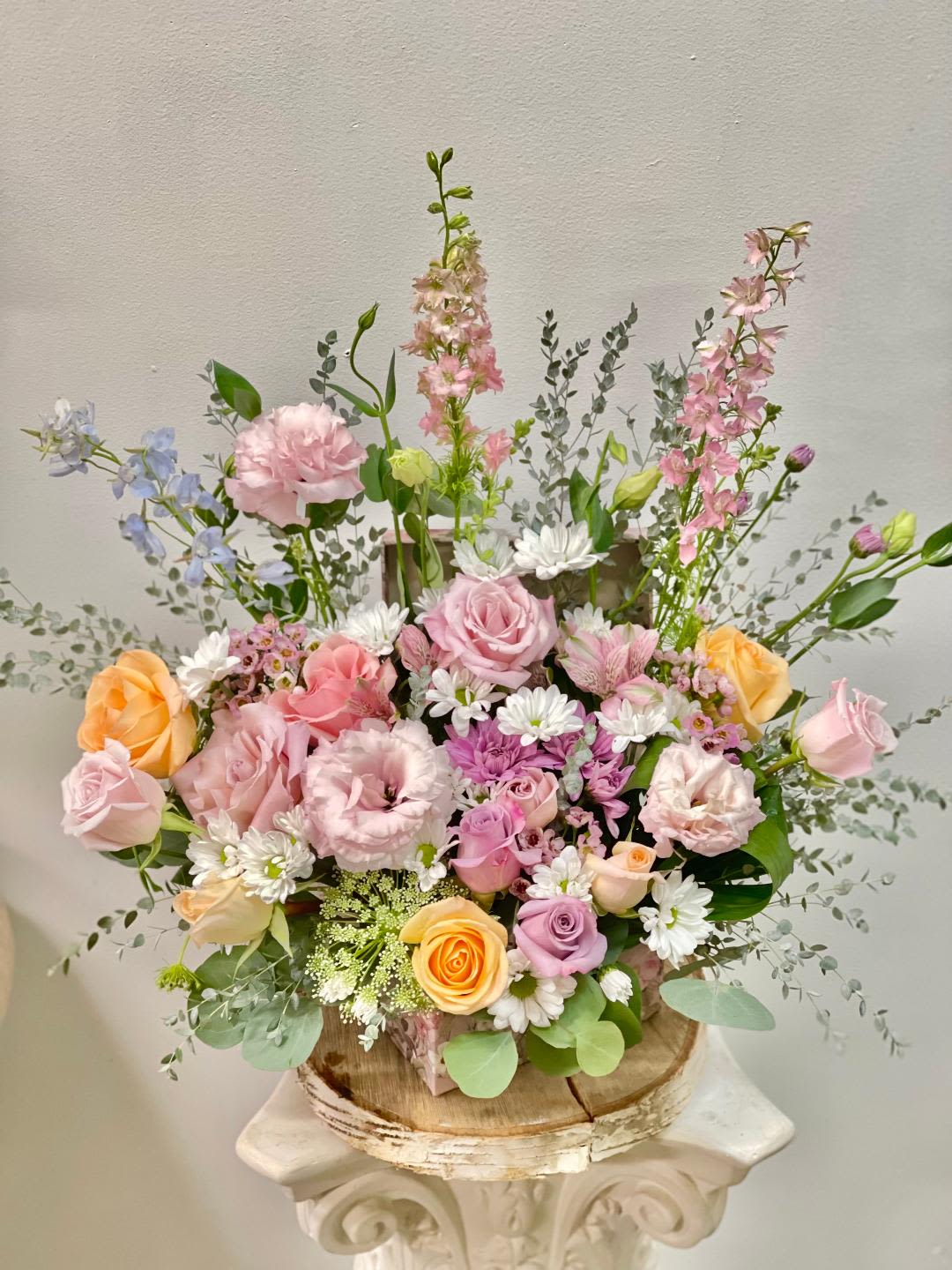Pastel mixed flower arrangement in a rustic wooden container