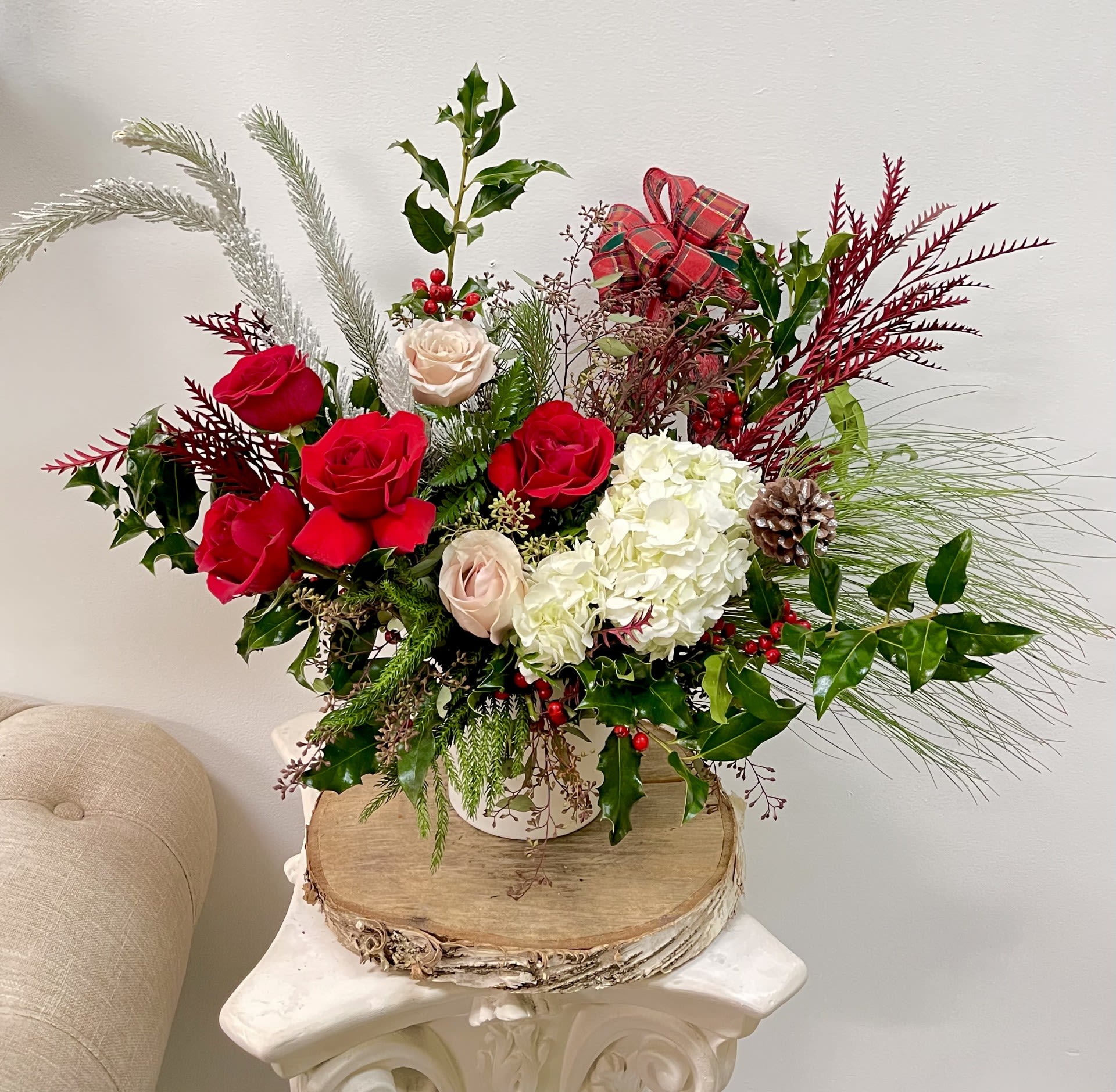 Holiday bouquet of red and white roses with pine and berries in a vase