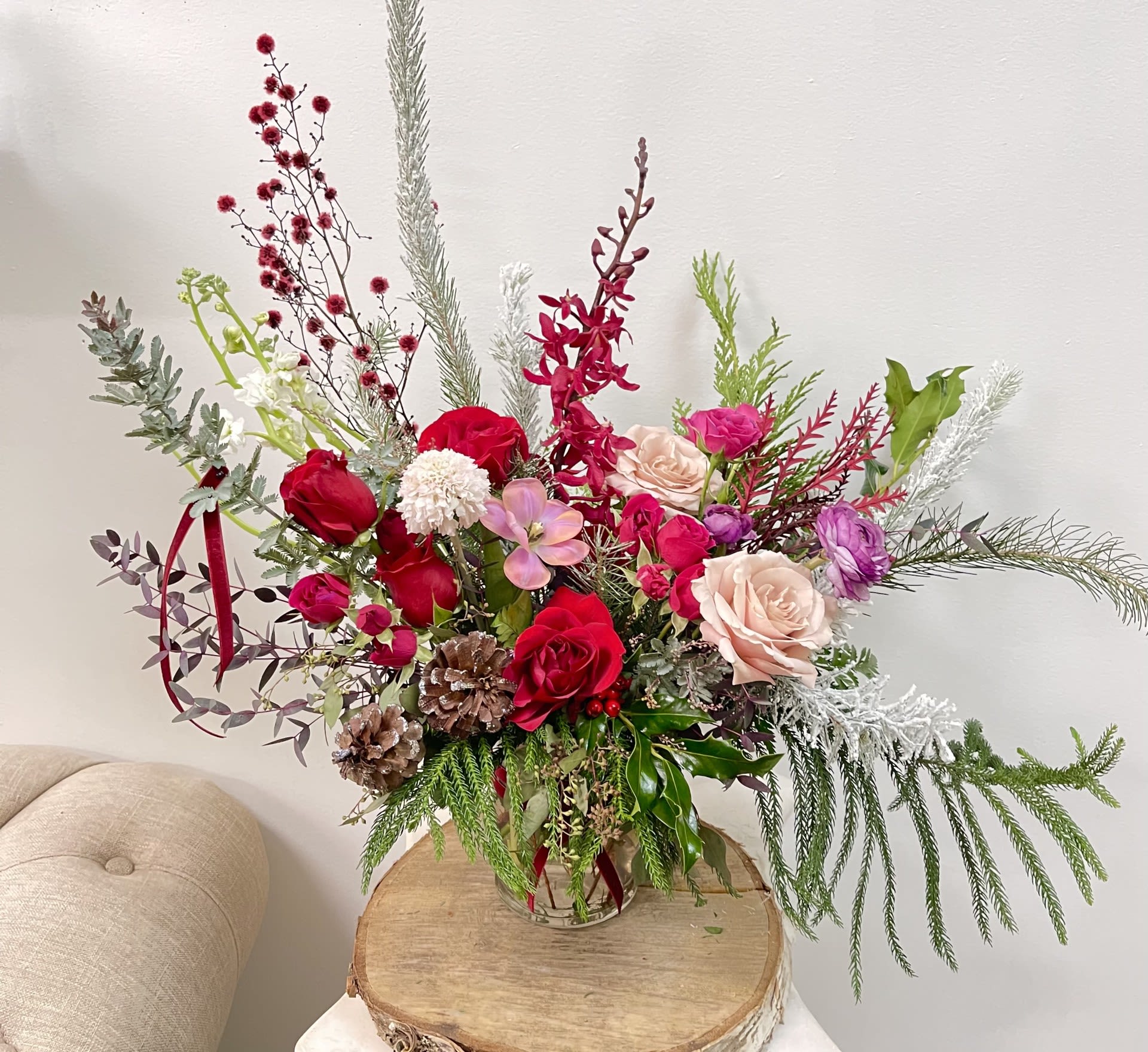 Tall mixed floral arrangement in a glass vase with red, pink, and white blooms
