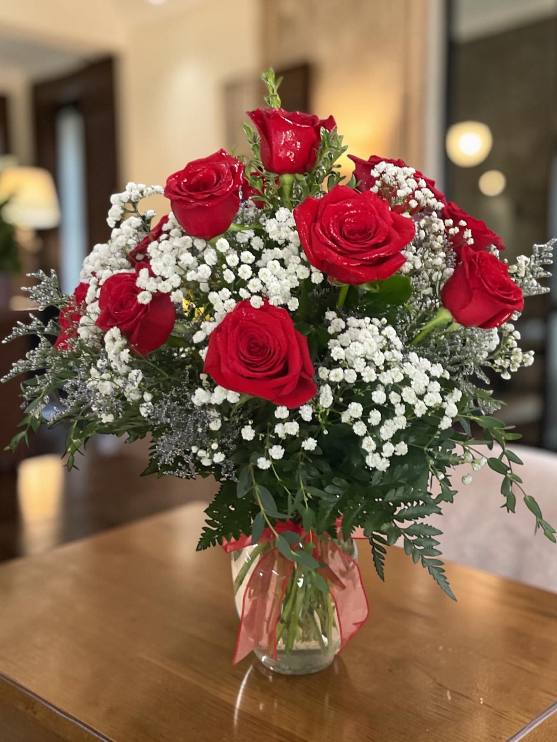 Dozen Red Roses - Classic Dozen Red Roses – Premium Long Stem Red Rose Arrangement  A dozen red roses is the most iconic way to say I love you—and this arrangement delivers it with style and substance.  Featuring twelve premium long-stem red roses, this bouquet is rich in color, full in shape, and designed for a clean, elegant presentation. Soft white accent flowers and fresh greenery add contrast and texture, creating a lush, balanced look that feels both timeless and refined.  This is the kind of red rose arrangement that makes an immediate impression—romantic, confident, and unmistakable.  Each rose is carefully selected for quality and freshness, then professionally arranged to ensure it arrives looking beautiful and continues to open gracefully in the days that follow. 
