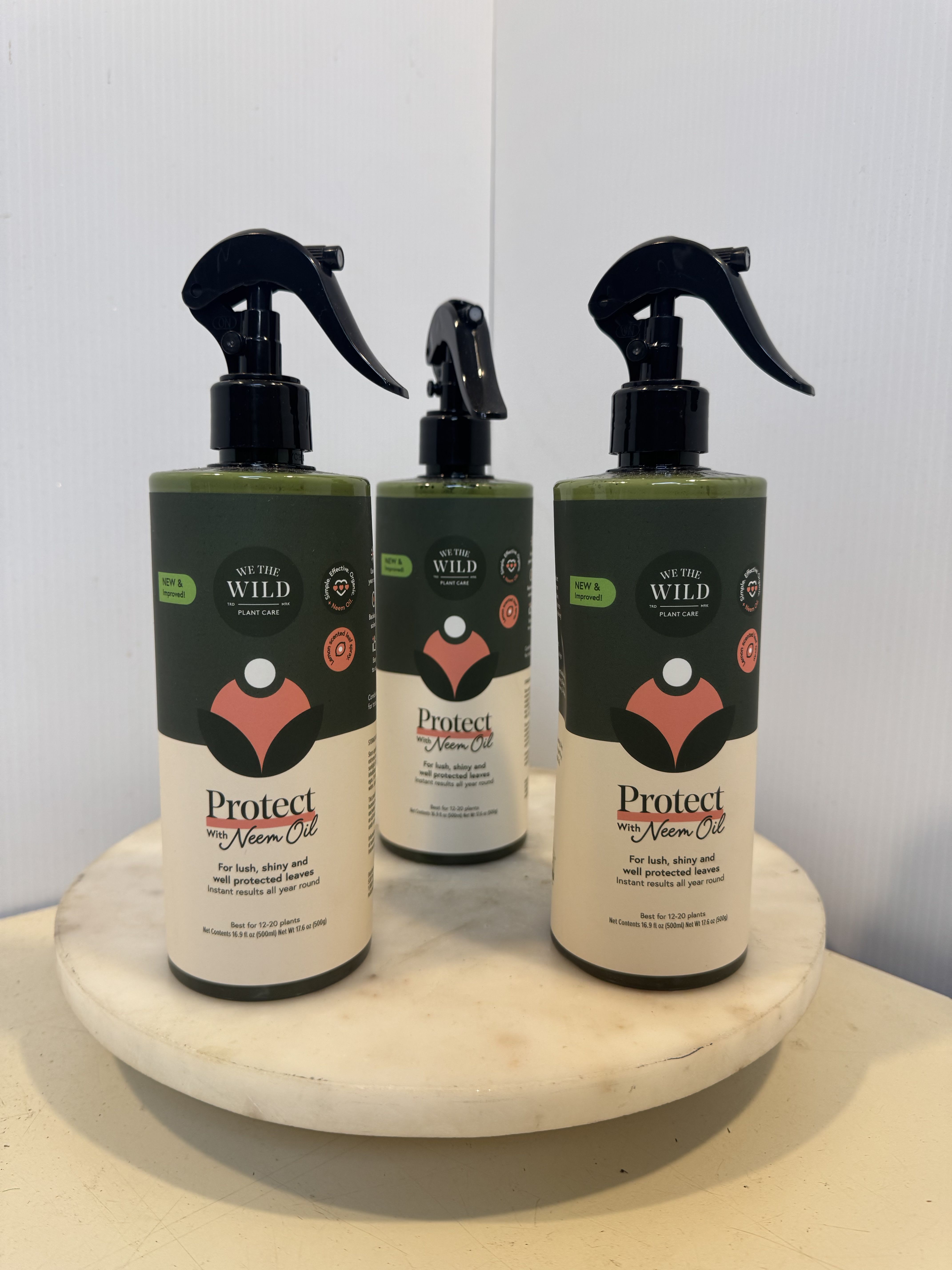 Three plant care spray bottles on a round marble stand