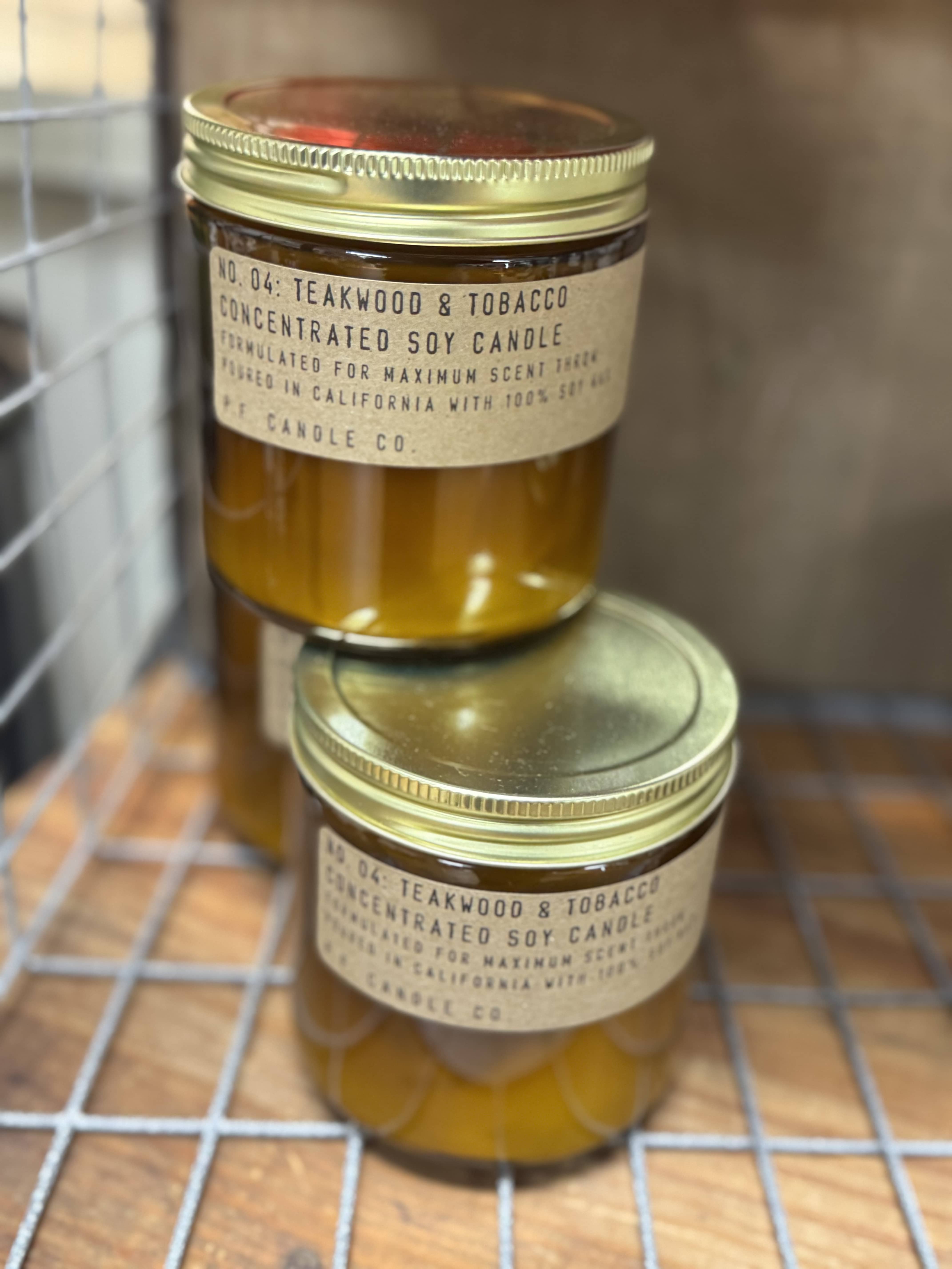 Two amber jar candles with gold lids stacked on a wire rack