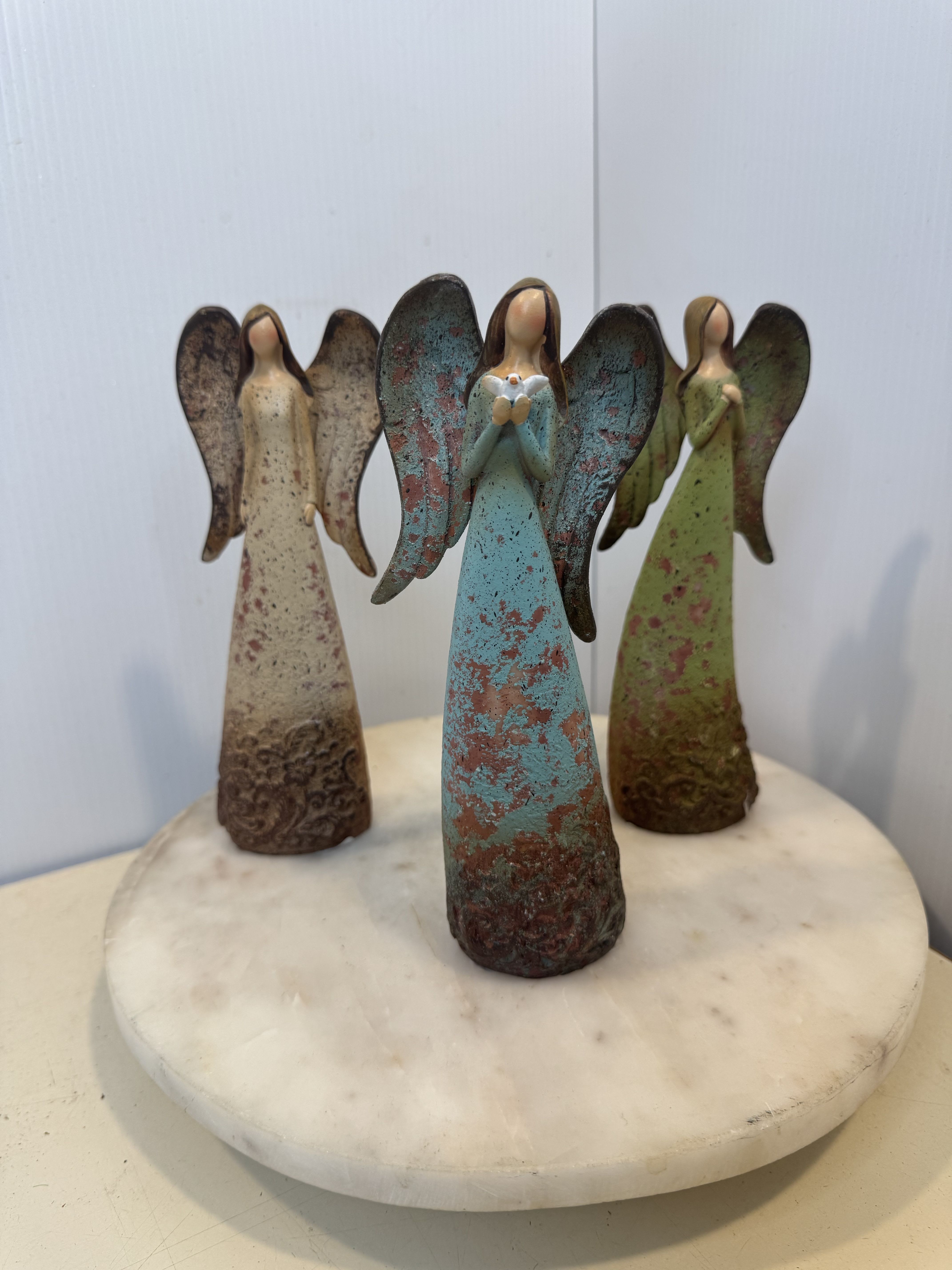 Three angel figurines standing on a round marble base