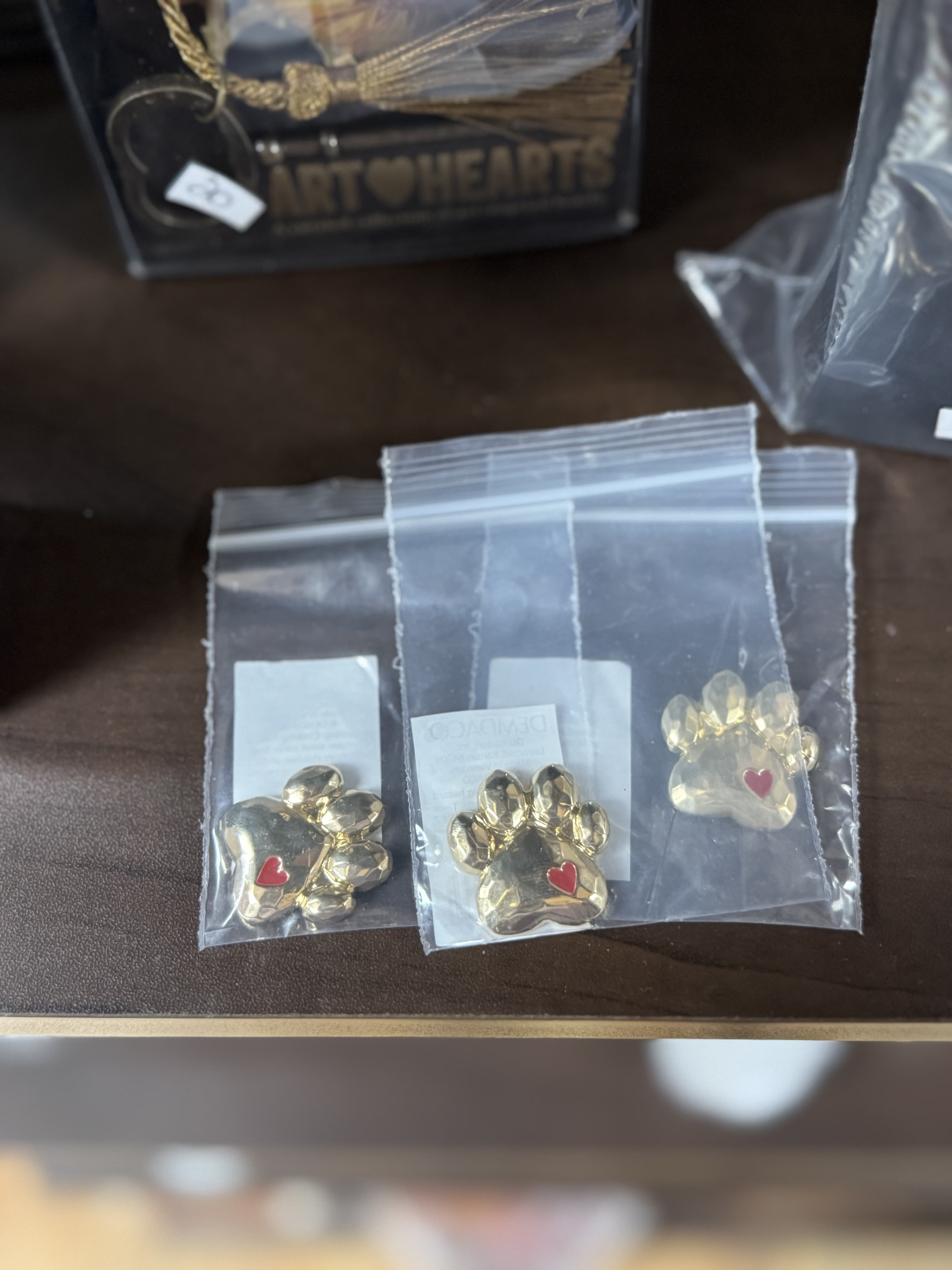 Three gold paw-print charms in clear plastic bags