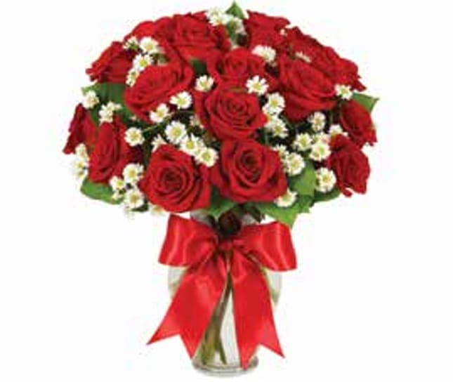 Bouquet of red roses with small white filler flowers in a glass vase