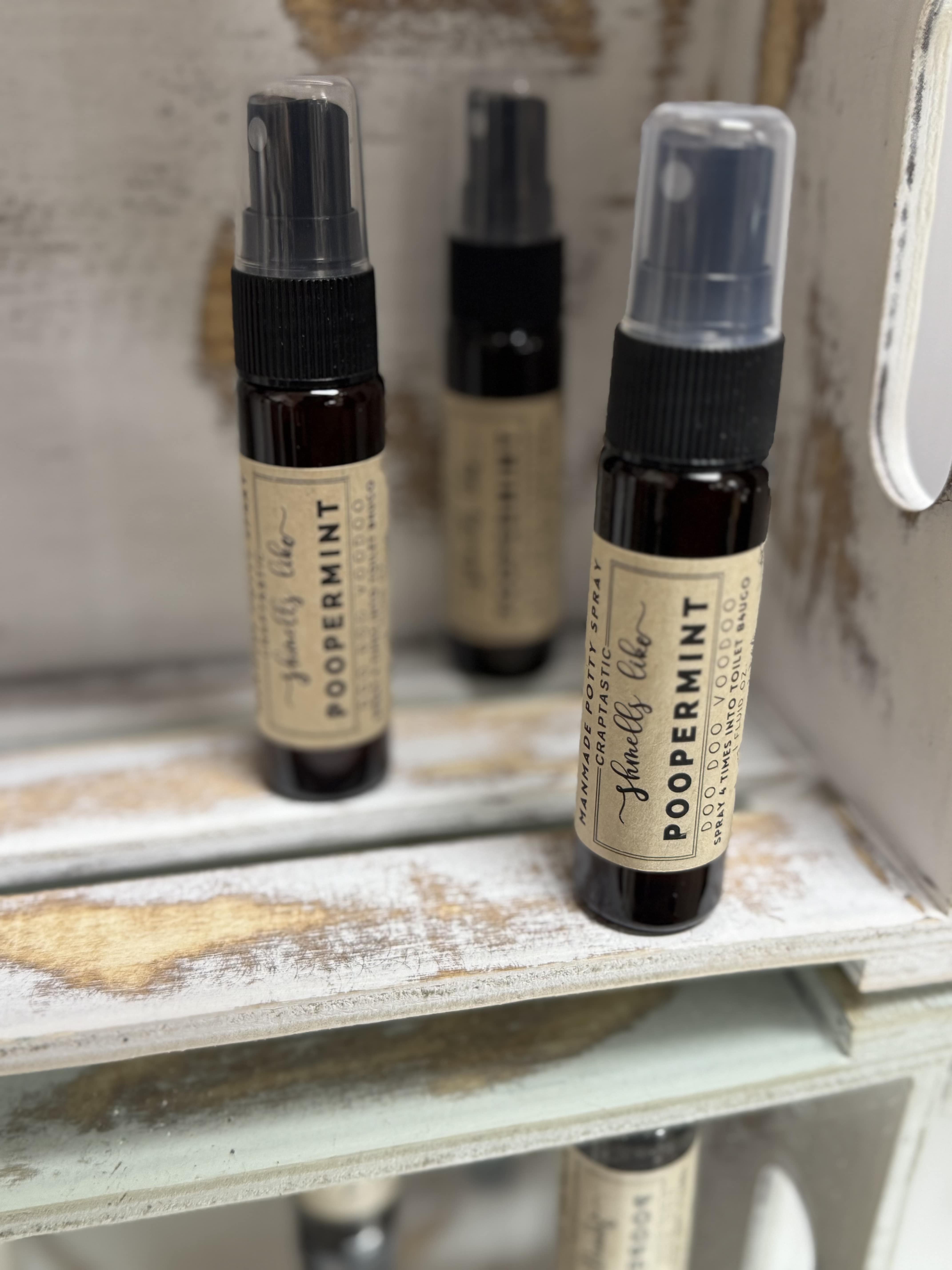 Three small spray bottles labeled peppermint sit on a shelf.