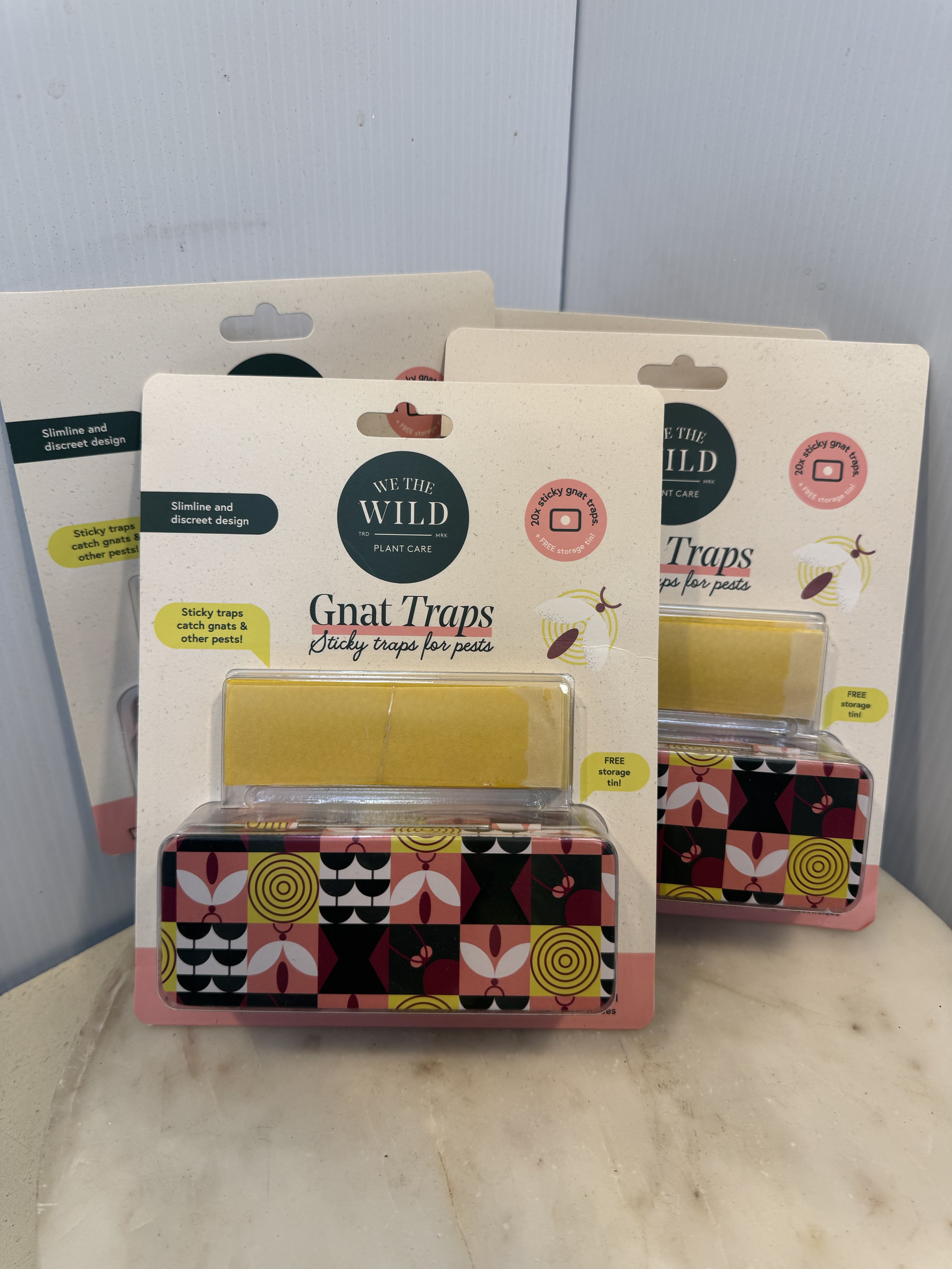 Three packaged gnat traps with patterned tins on a tabletop