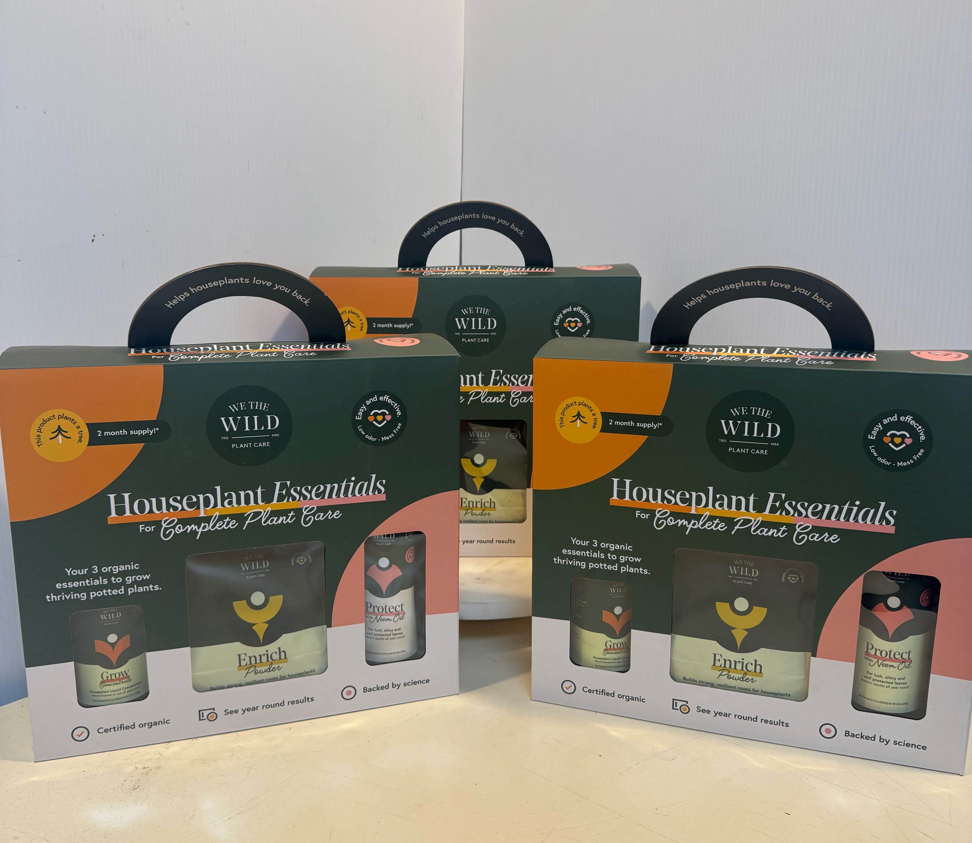 Three houseplant care kits in dark green and orange boxes.
