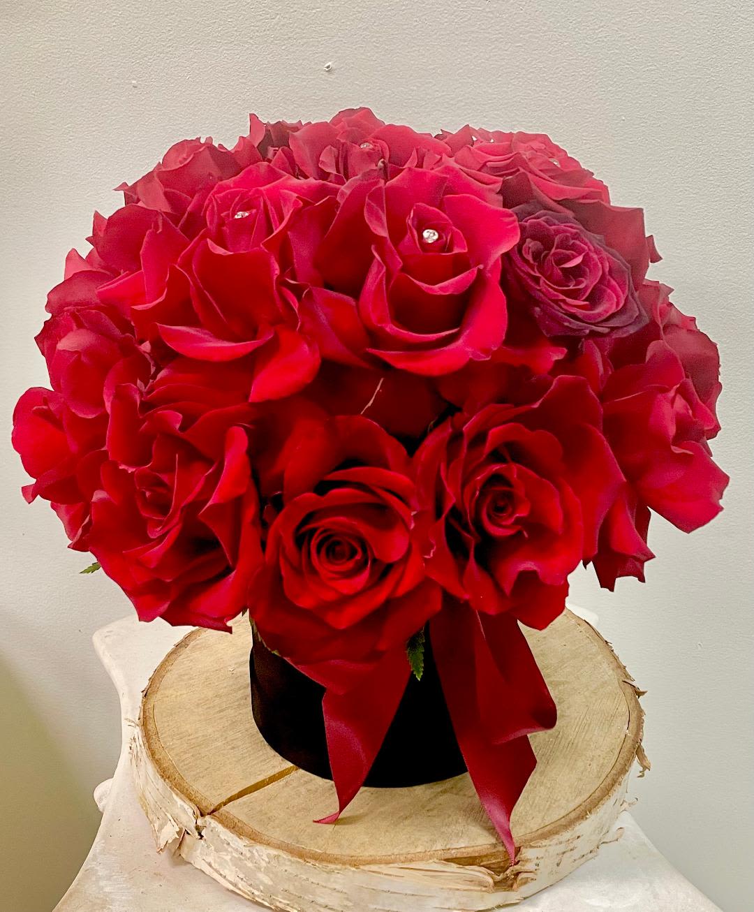 Red rose bouquet in a black vase with a red ribbon