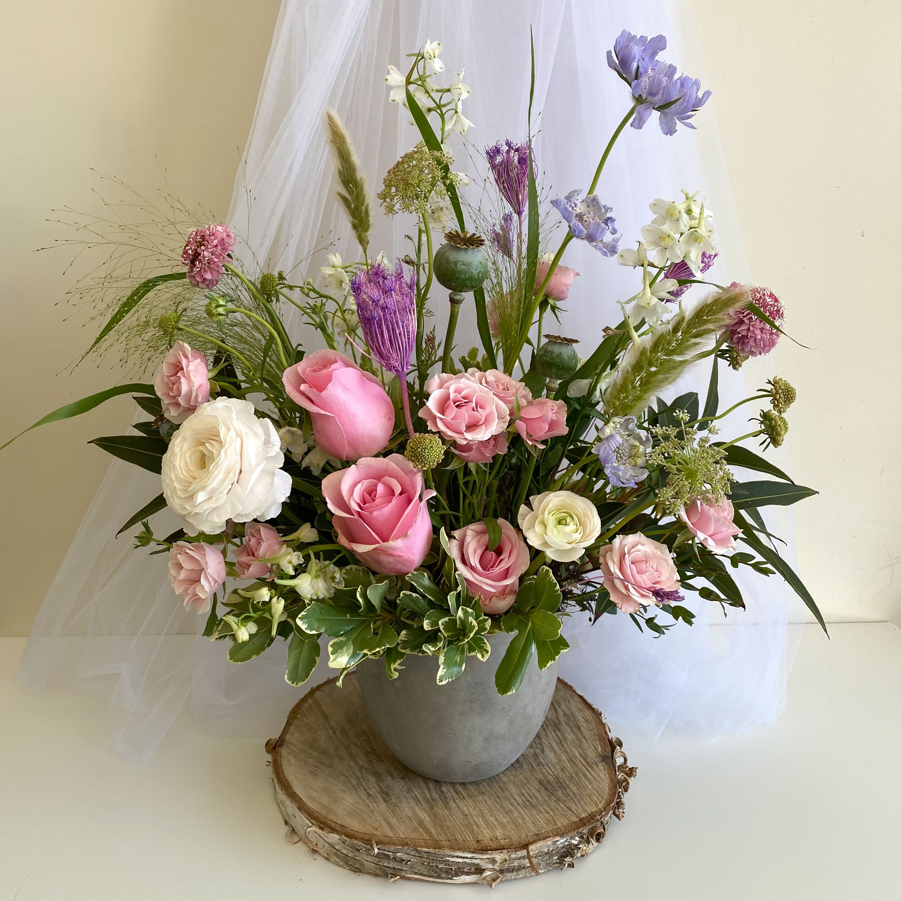 Pink and white roses with purple flowers in a gray vase