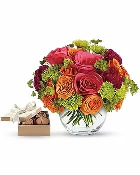 SMILE FOR. ME WITH CHOCOLATES - Share happy feelings with this sweet array of hot pink roses, orange spray roses, purple carnations and more in a sparkling glass bubble bowl with a box of chocolates! 