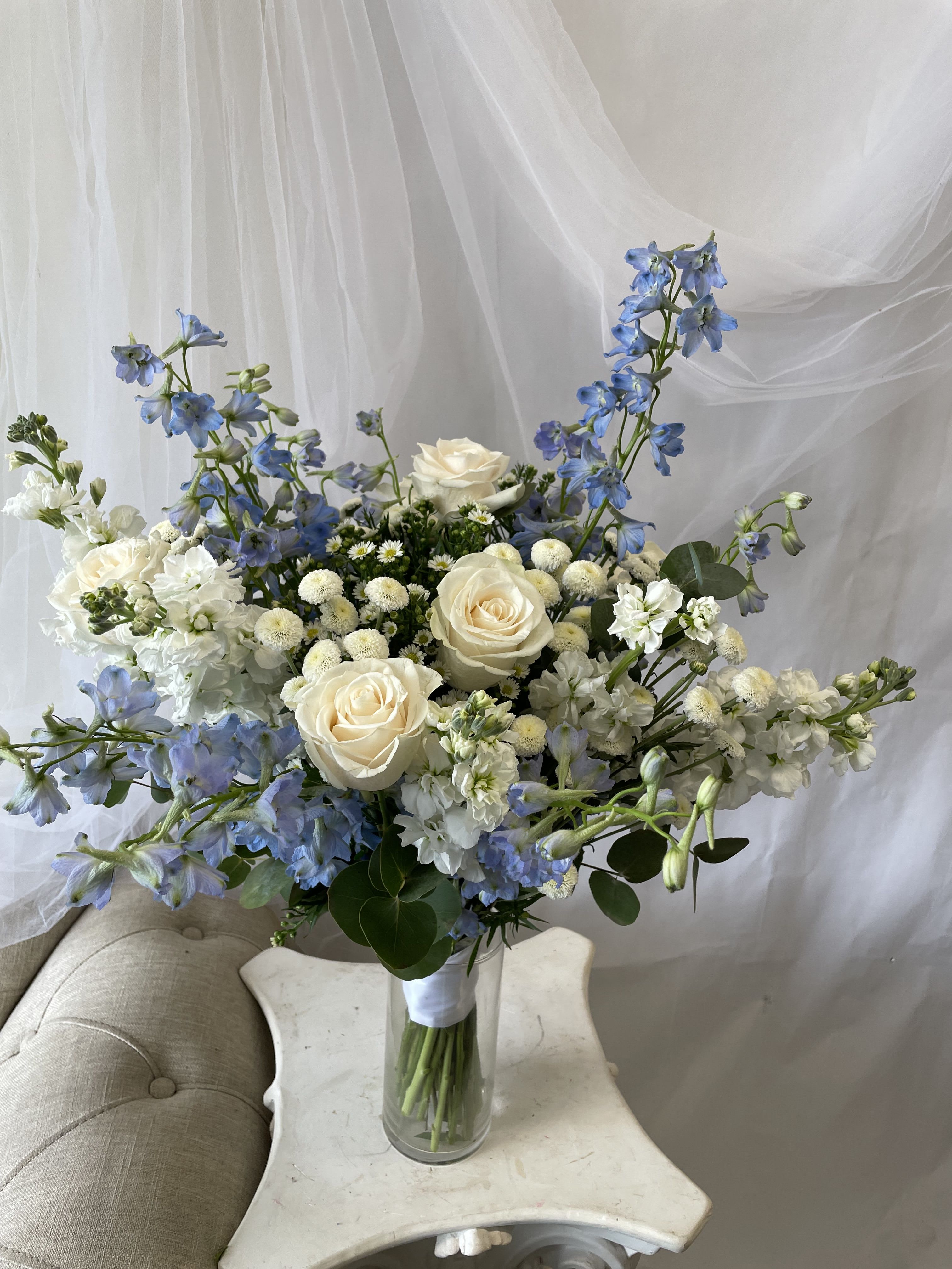Blue and white bouquet with roses in a clear glass vase