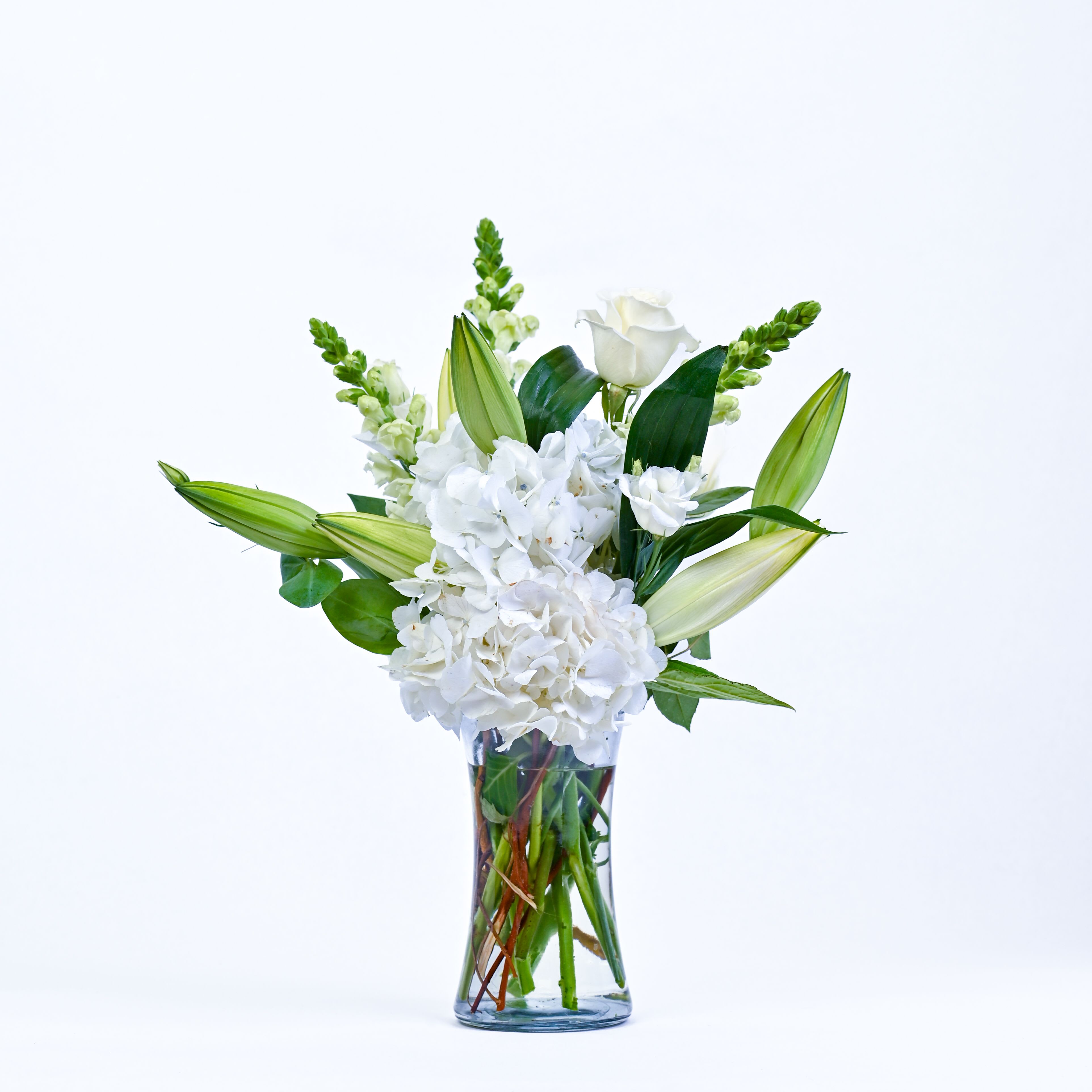 White flowers and lily buds arranged in a clear glass vase