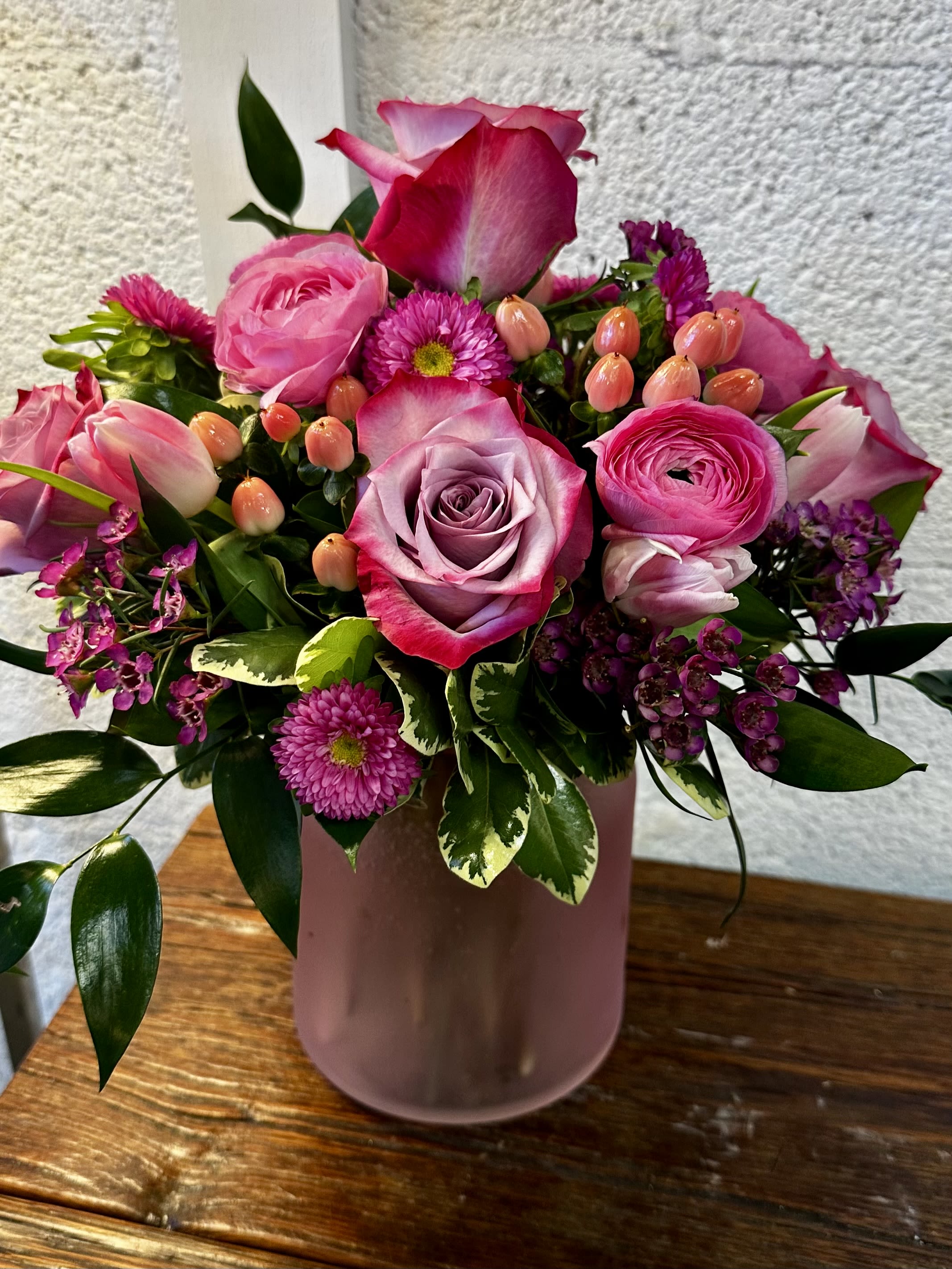 Pink Perfection  - Pink and lavender roses with ranunculus, chrysanthemums and greens in a matte mauve ceramic vase-soft, romantic bouquet for birthdays, anniversaries or to say "thinking of you. 