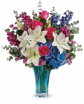 Ocean Dance Bouque - Hot pink roses, white asiatic lilies, blue hydrangea, fuchsia stock, blue delphinium, and raspberry sinuata statice are arranged with lemon leaf and spiral eucalyptus. Delivered in a Heart's Pirouette vase. 