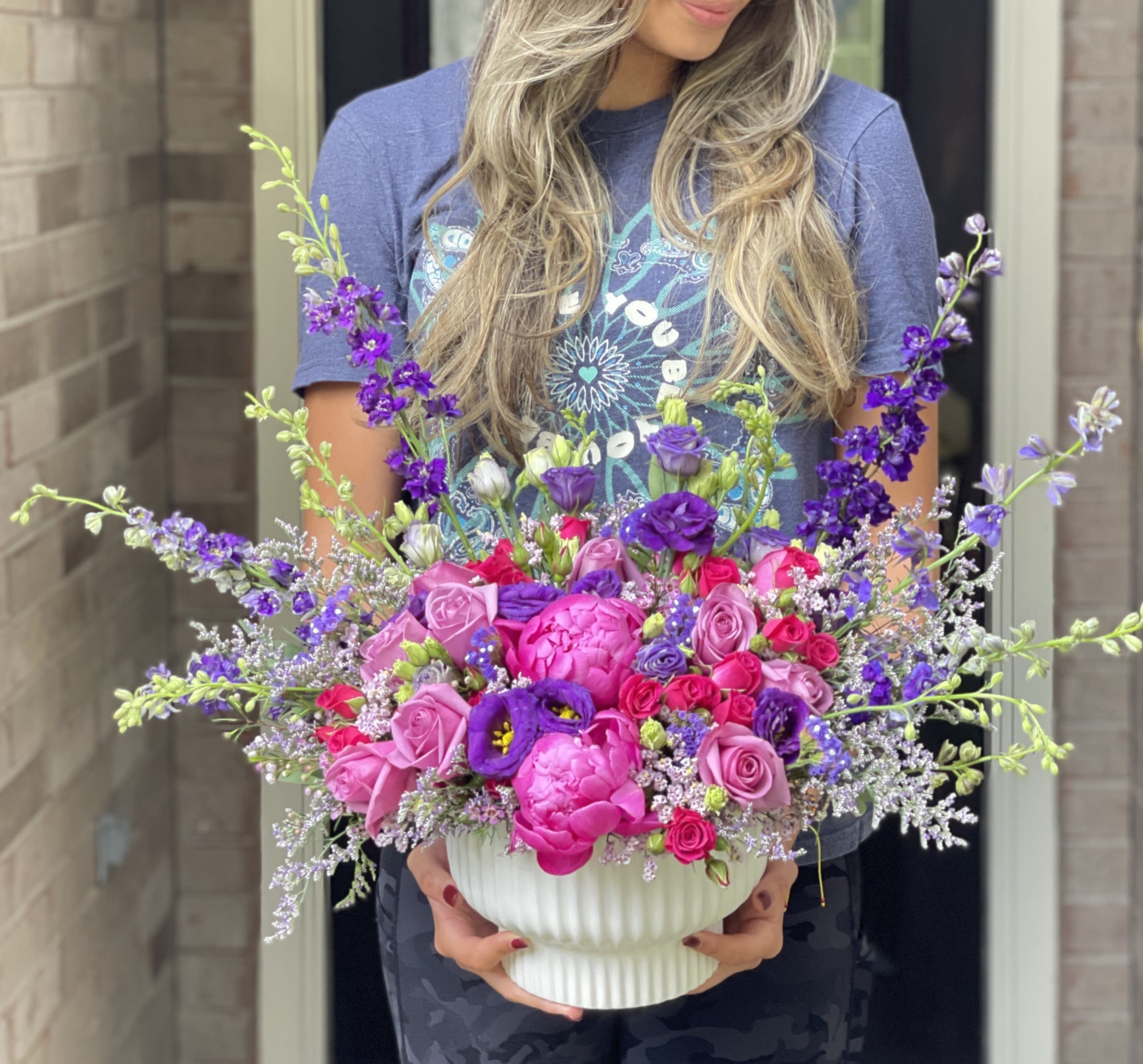 Large pink and purple flower arrangement in a white vase
