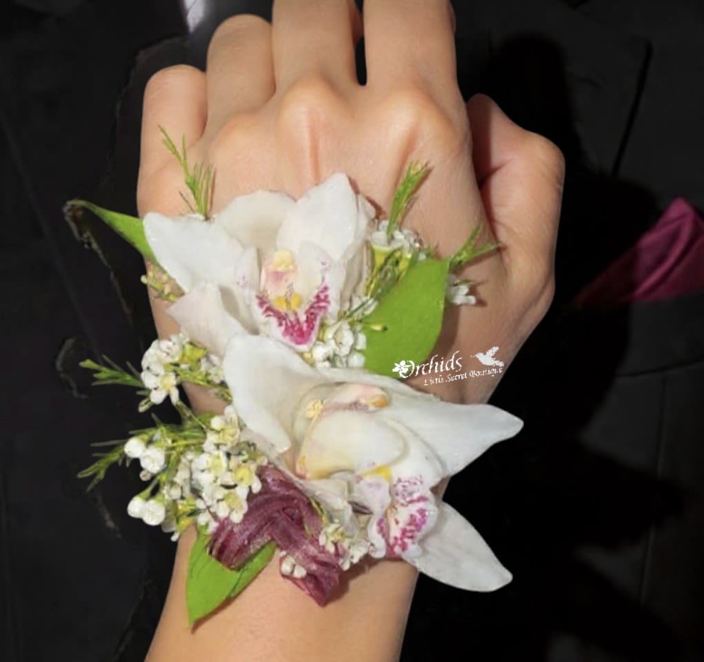 Cymbidium Orchids Corsage  Wax Flower &amp; Burgundy Ribbon - Elegant Cymbidium orchid corsage, designed for timeless beauty. Features a premium Cymbidium orchid bloom accented with delicate wax flowers, creating a soft, romantic texture. Finished with a rich burgundy ribbon, this corsage adds a refined pop of color—perfect for proms, weddings, homecomings, and special celebrations. Each corsage is handcrafted with care to ensure freshness, style, and a comfortable fit.  Ideal for those searching for a corsage near Placentia or a luxury orchid corsage in Orange County, this design offers a modern yet classic floral statement.  Features:  Fresh Cymbidium orchid bloom Accented with delicate wax flowers Elegant burgundy ribbon finish Perfect for prom, weddings, and formal events   Local Delivery &amp; Pickup: Available for  pickup or local delivery in Placentia, Yorba Linda, Fullerton, and surrounding Orange County areas.