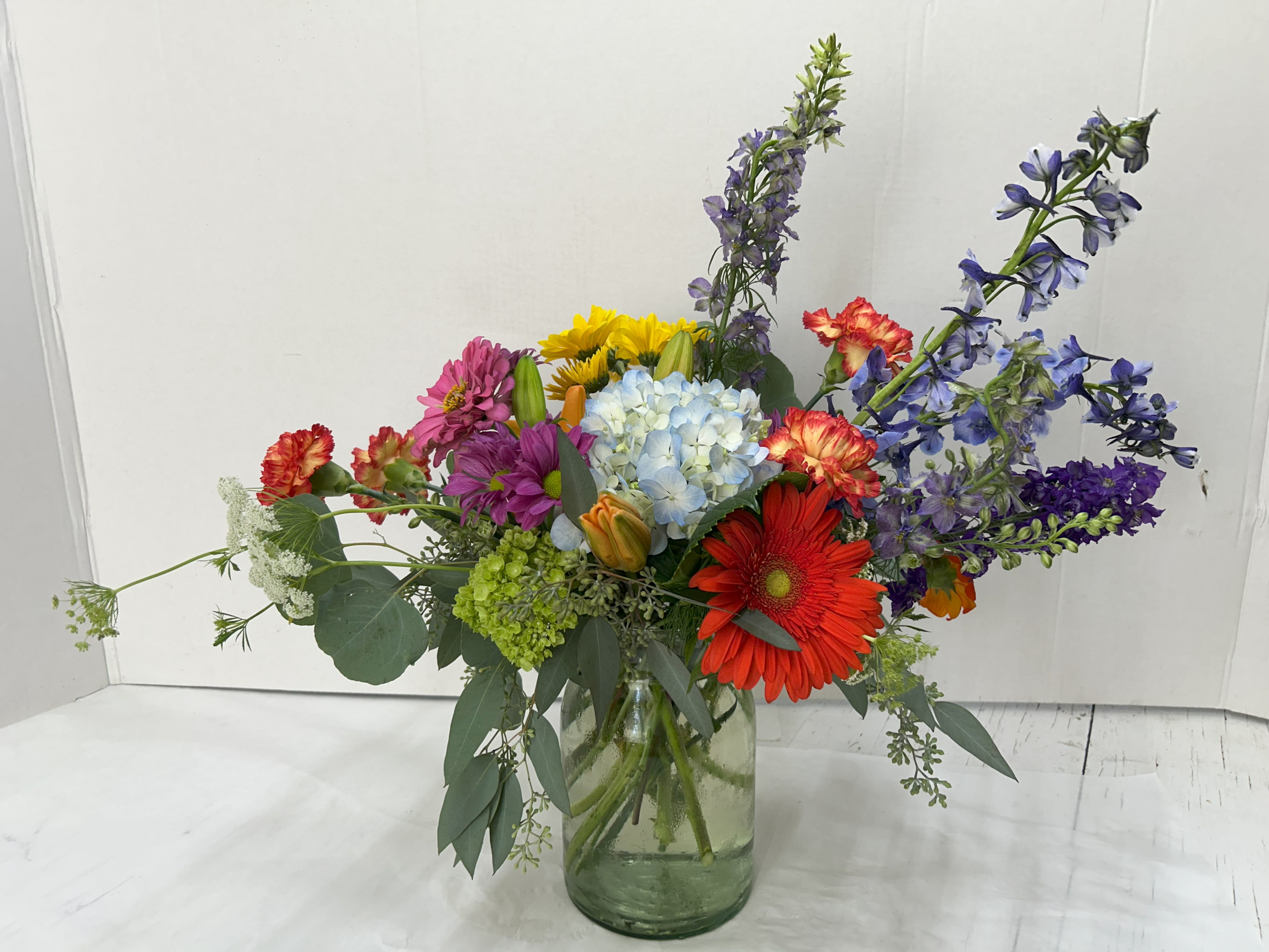 Colorful mixed bouquet in a glass vase with tall purple blooms