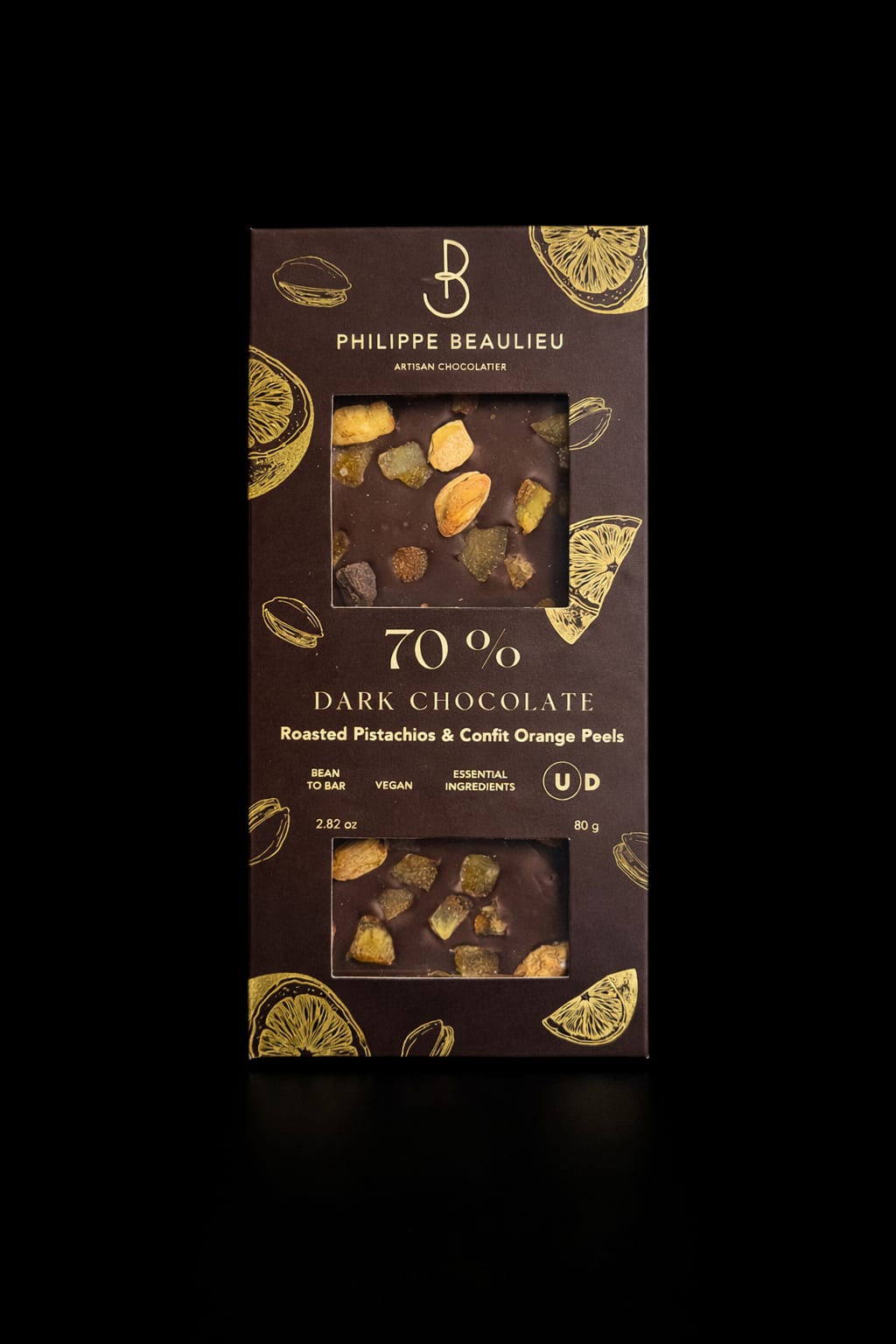 Dark Chocolate - A luxe dark chocolate bar crafted for gifting, perfect as an indulgent add-on for anniversaries, thank-you gestures, or to celebrate small victories. The boxed presentation-black packaging with gold citrus illustrations, white typography, and a clear window-shows off the glossy dark chocolate studded with roasted pistachios and candied orange peel so the recipient immediately senses the artisanal quality.  Expect deep, bittersweet chocolate punctuated by crunchy pistachio pieces and bright, chewy orange peel for a complex flavor contrast. The bar comes in a windowed box that highlights the toppings and texture, making it a thoughtful complement to a bouquet or a standalone treat for someone who appreciates gourmet confections.
