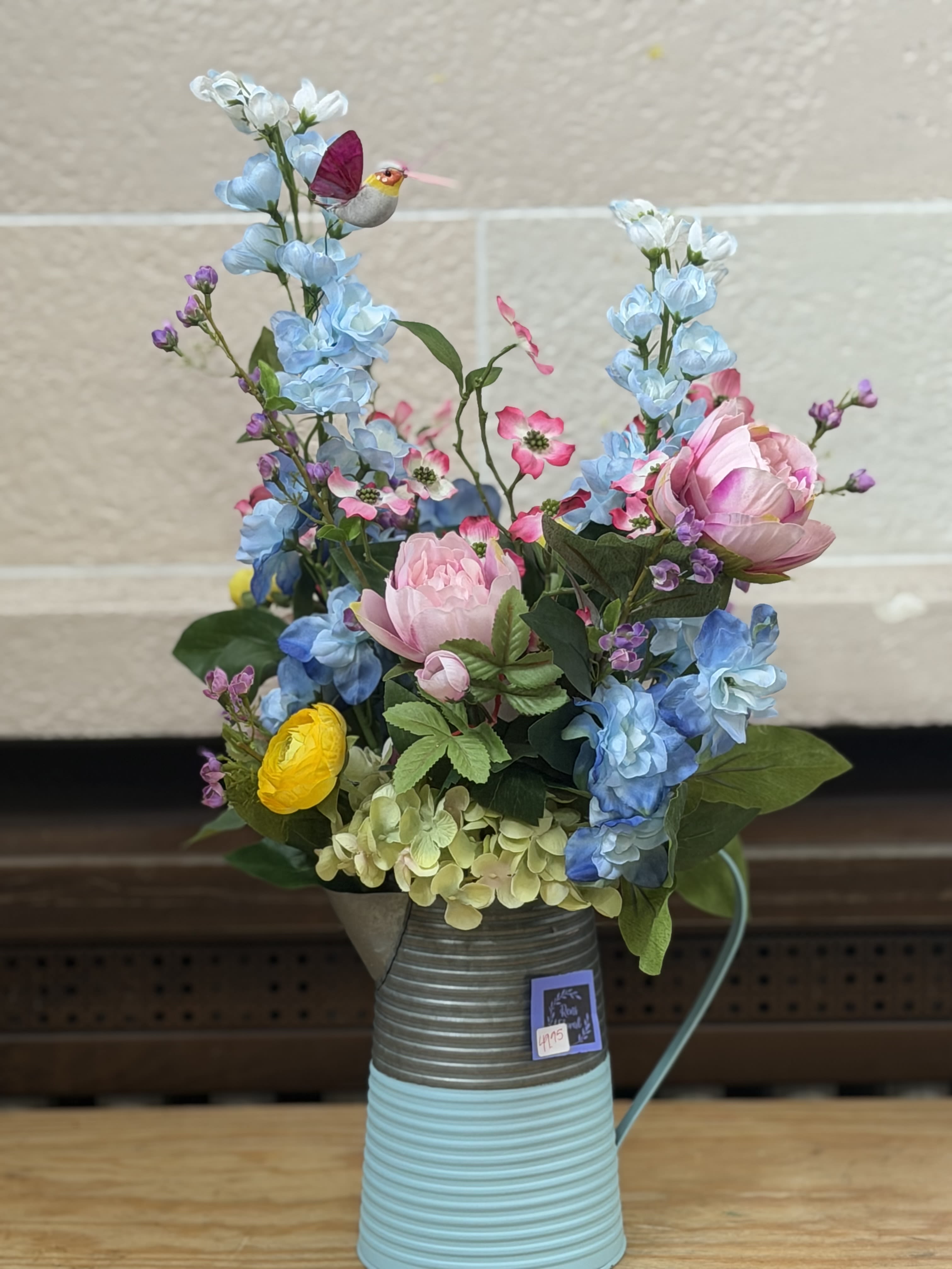 Hummingbird Pitcher - Artificial Arrangement - A pitcher vase filled with colorful artificial blooms and a hummingbird pick. 