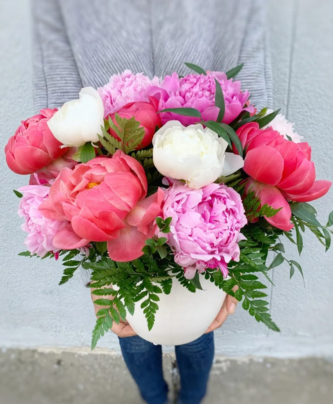 Pink and white peonies arranged in a white vase